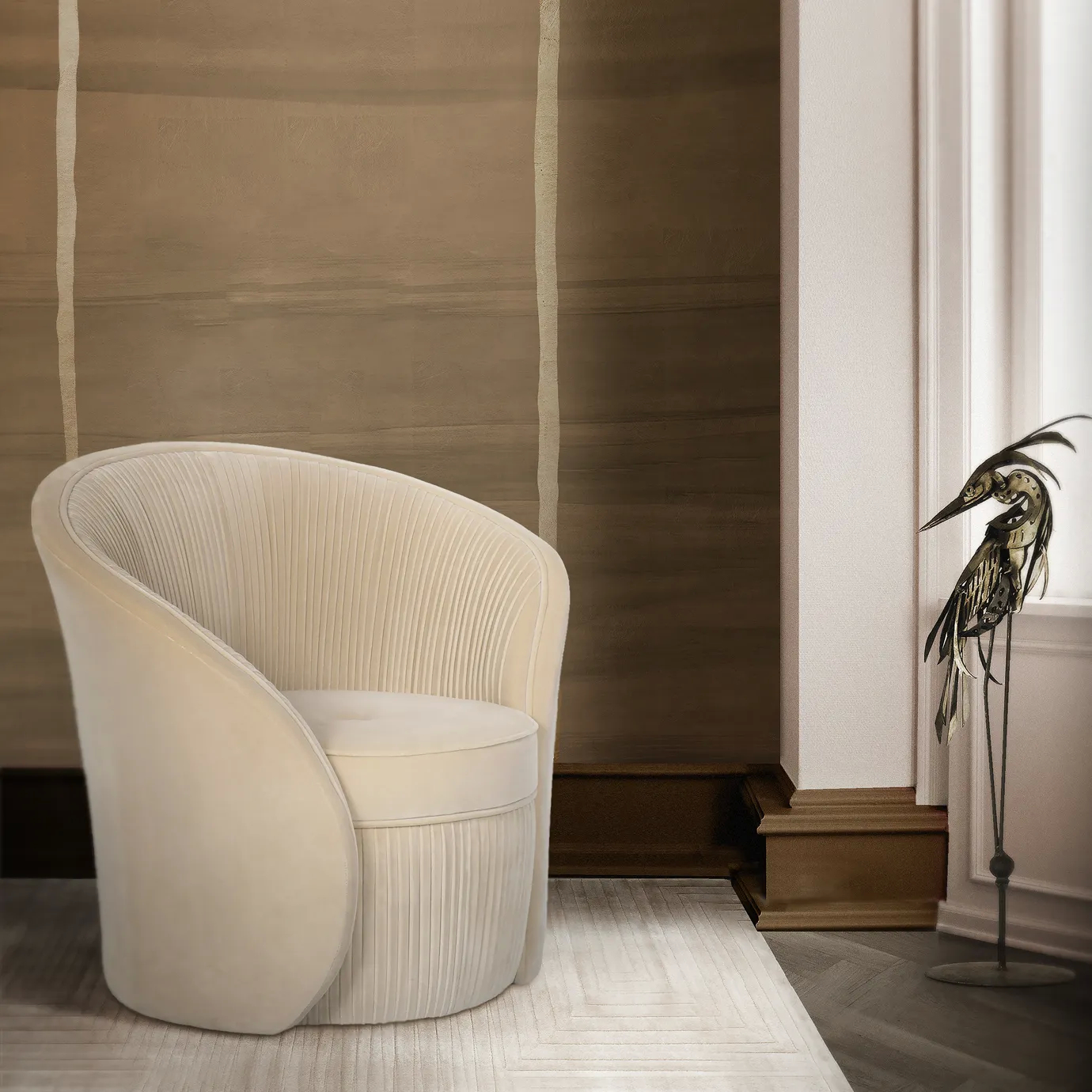 Elegant corner with the Bloom Armchair upholstered in soft beige fabric with a rounded design and vertical pleated details on the base and backrest, on a light rug with a subtle geometric pattern, next to a metallic bird sculpture and in front of a textured beige and brown-toned wall with lighter vertical details.
