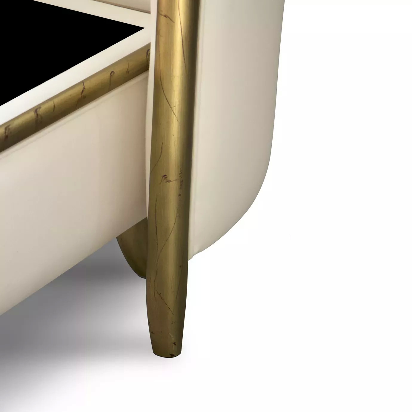 Elegant close-up of the slightly curved golden leg detail of the Forbidden Plain Bed, with the light beige fabric upholstered frame and golden accents visible.