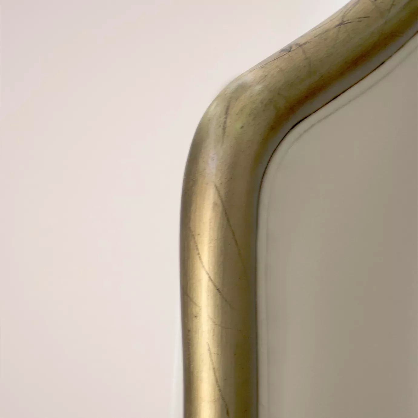 Elegant close-up of the curved golden trim detail of the light beige fabric upholstered headboard of the Forbidden Plain Bed.