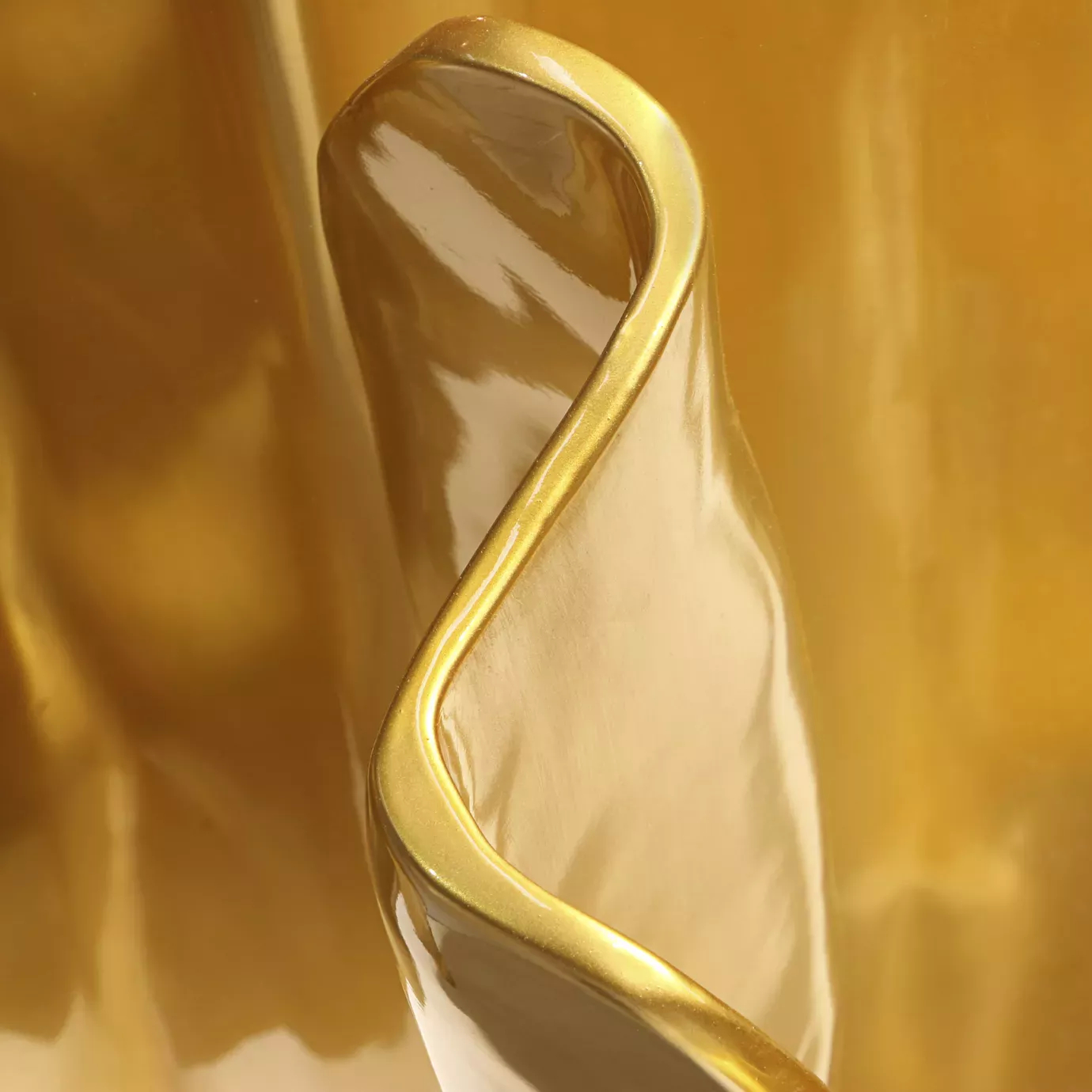 Elegant close-up of the fluid golden texture of the Obssedia Dining Table base.