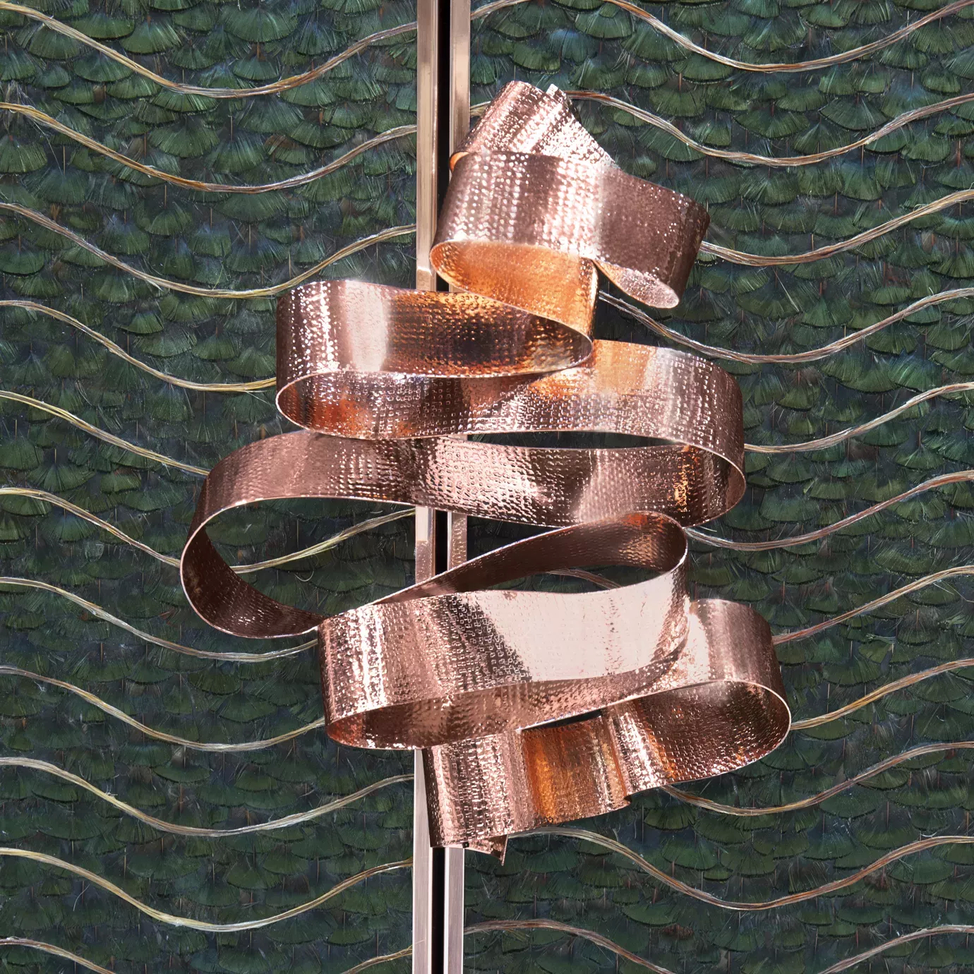 Detailed vision of the copper ribbon handle on the front doors of the Divine Peacock Organic Feather Armoire, combining with the caramel and dark green peacock feathers.