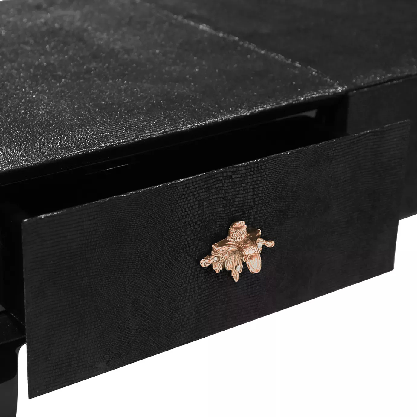 Elegant close-up of a slightly opened black drawer of the Luridae Console, revealing the dark interior and the decorative copper-toned handle with a floral or star-like design.