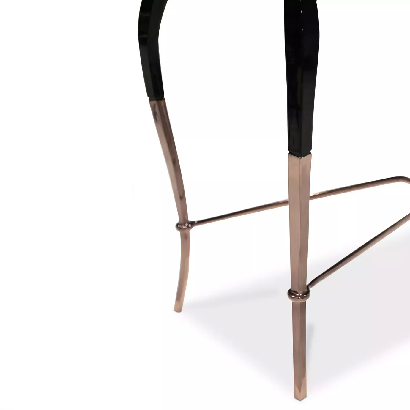 Elegant close-up detail of the curved black and copper legs of the Luridae Console, showing the sculptural copper connection at the base.