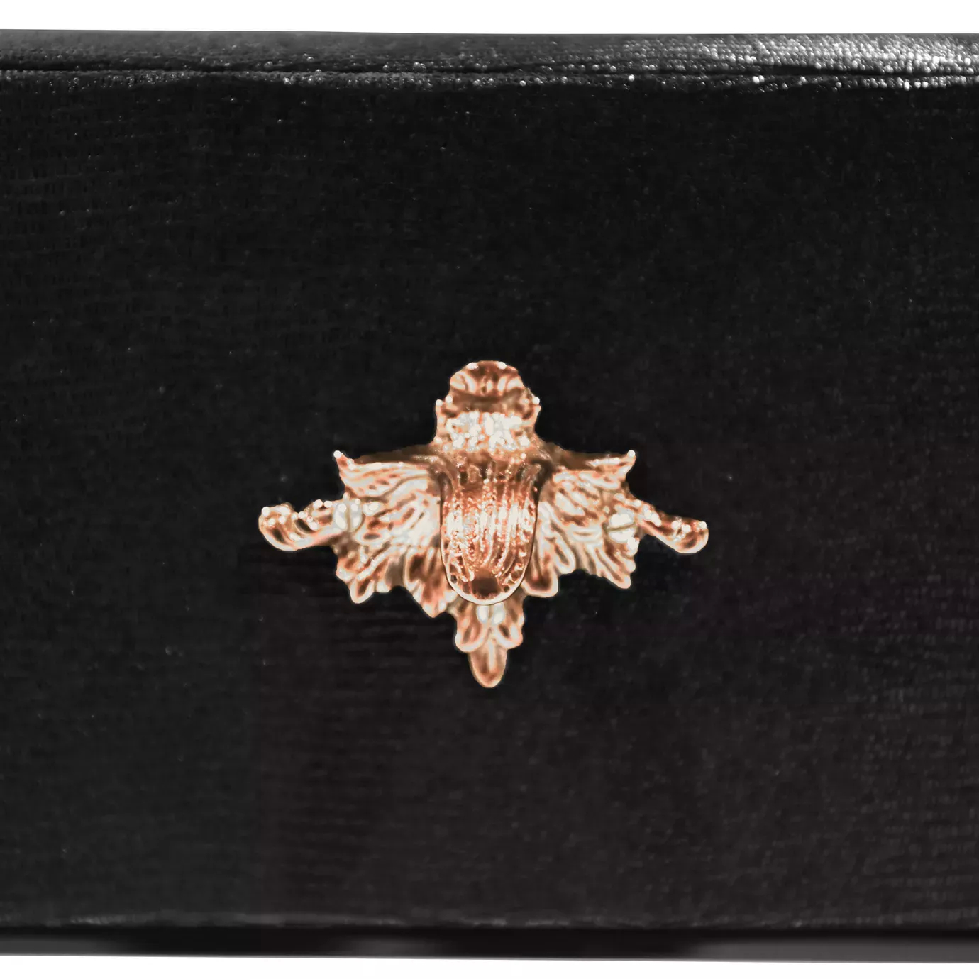 Elegant close-up detail of a decorative copper-toned handle with an intricate floral or foliage design on a black drawer of the Luridae Console.