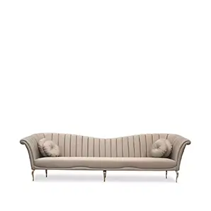 Elegant Long Caprichosa Sofa with a golden metal base and soft beige fabric upholstery featuring a wavy design on the backrest and two round cushions at the ends.