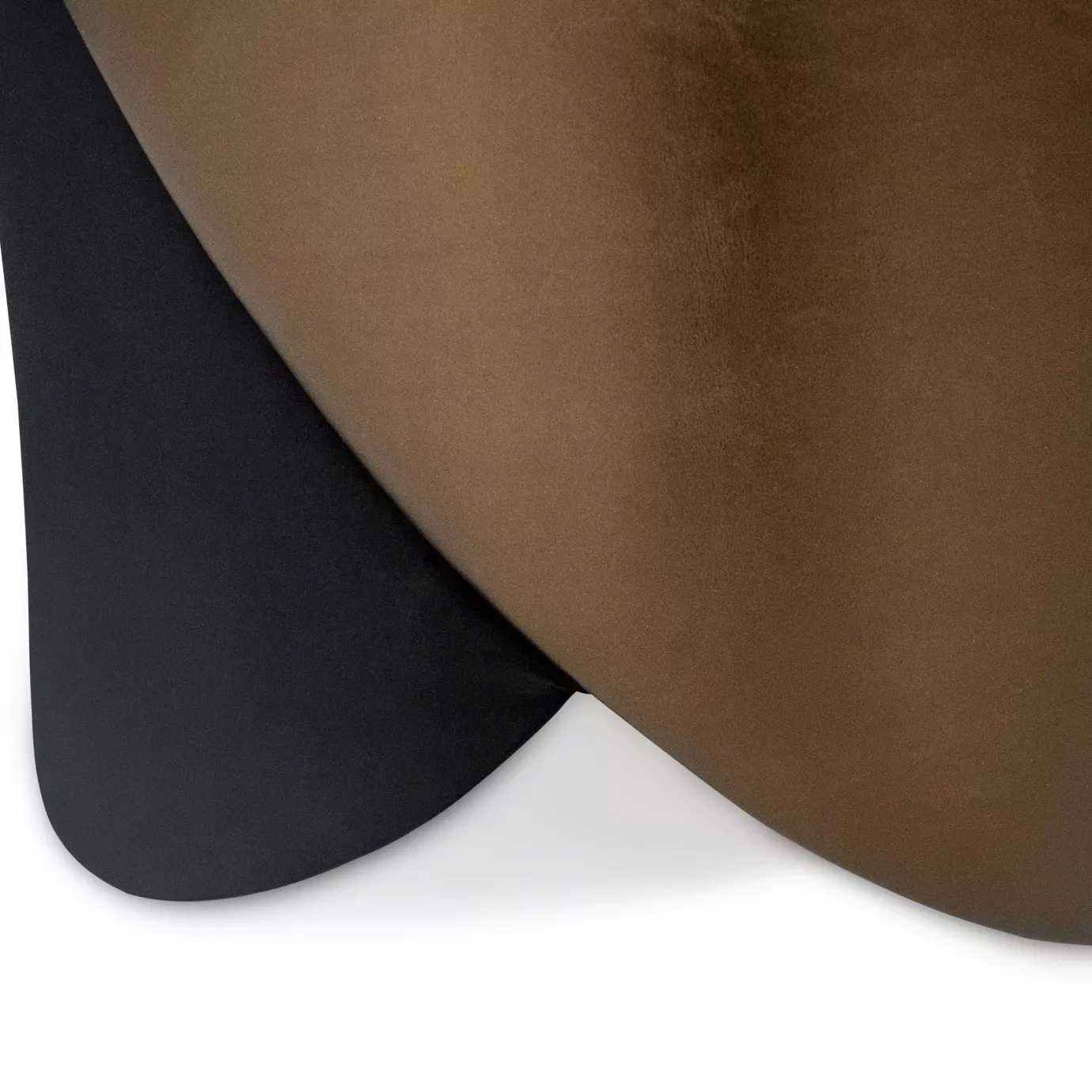 Elegant close-up detail of the contrast between the soft black fabric and the bronze-toned side panel of the Denise Chair.