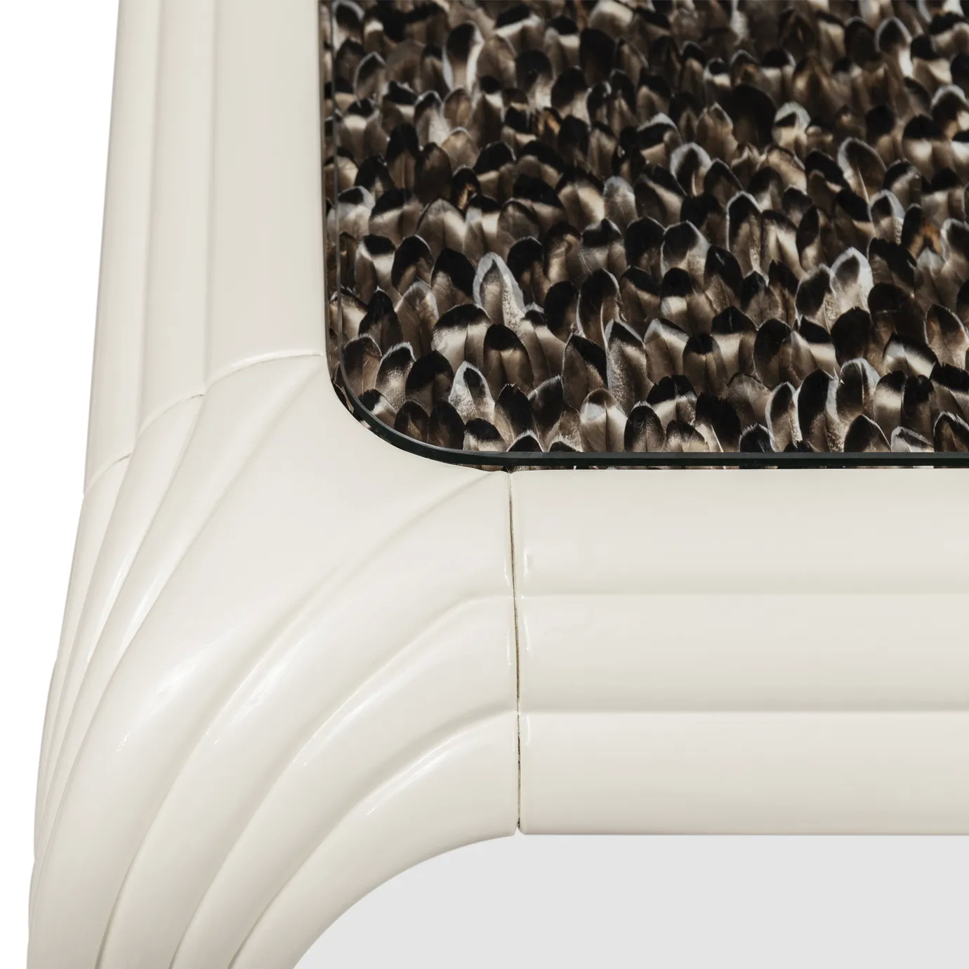 Elegant close-up detail of the rectangular tabletop of the Merveille Dining Table adorned with an exotic feather pattern in shades of brown and black, and its smooth connection to the curved white base with vertical textured details.