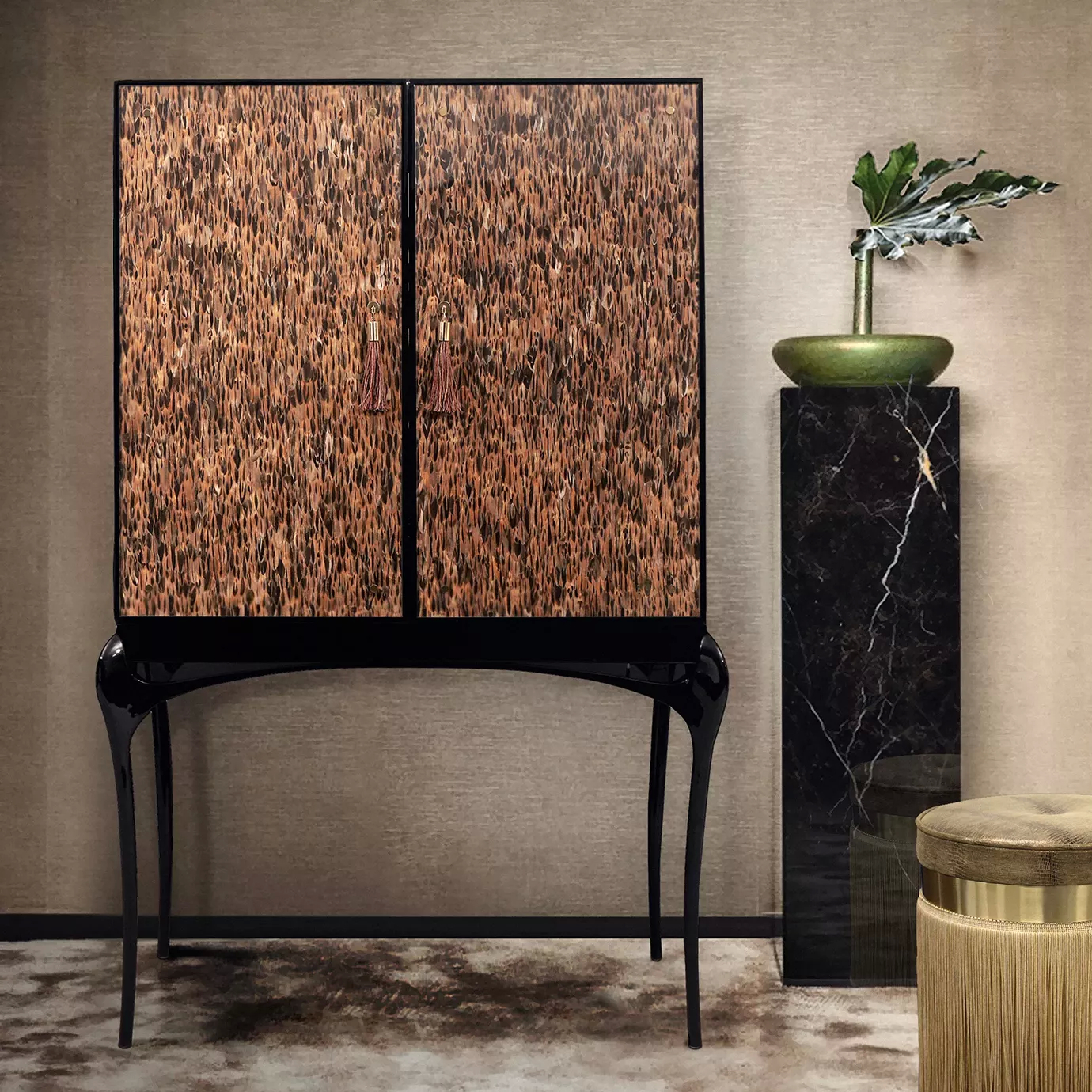 Elegant living room corner featuring the Temptation Bar Cabinet with doors adorned with a golden and brown feather pattern, copper-toned handles with tassels, and a glossy black frame with curved legs, next to a tall black marble pedestal with a green vase and a plant, and a round beige upholstered pouf with golden details, against a neutral-toned textured wall and a light rug.