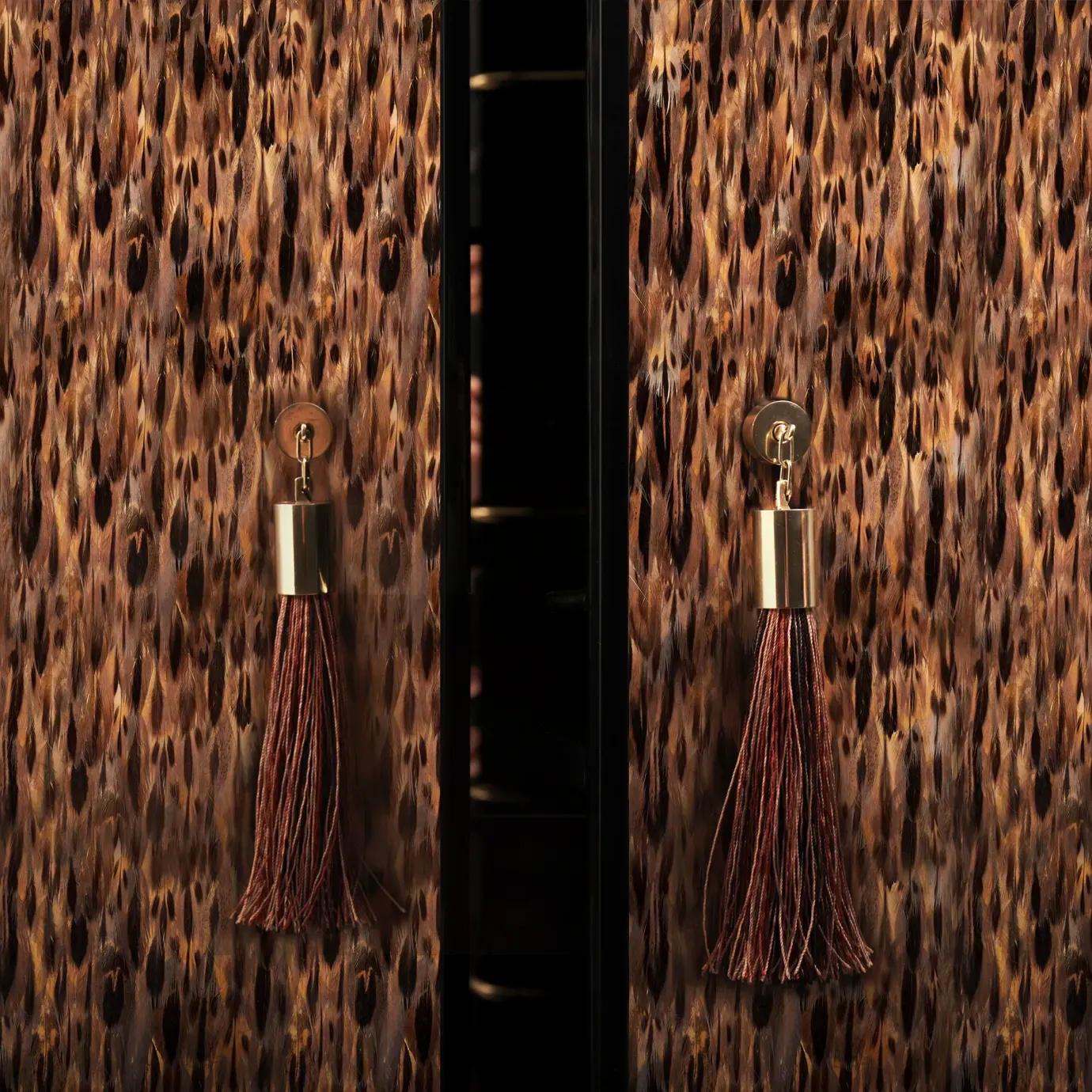 Elegant close-up detail of the doors of the Temptation Bar Cabinet adorned with a golden and brown feather pattern and copper-toned handles with decorative brown tassels.