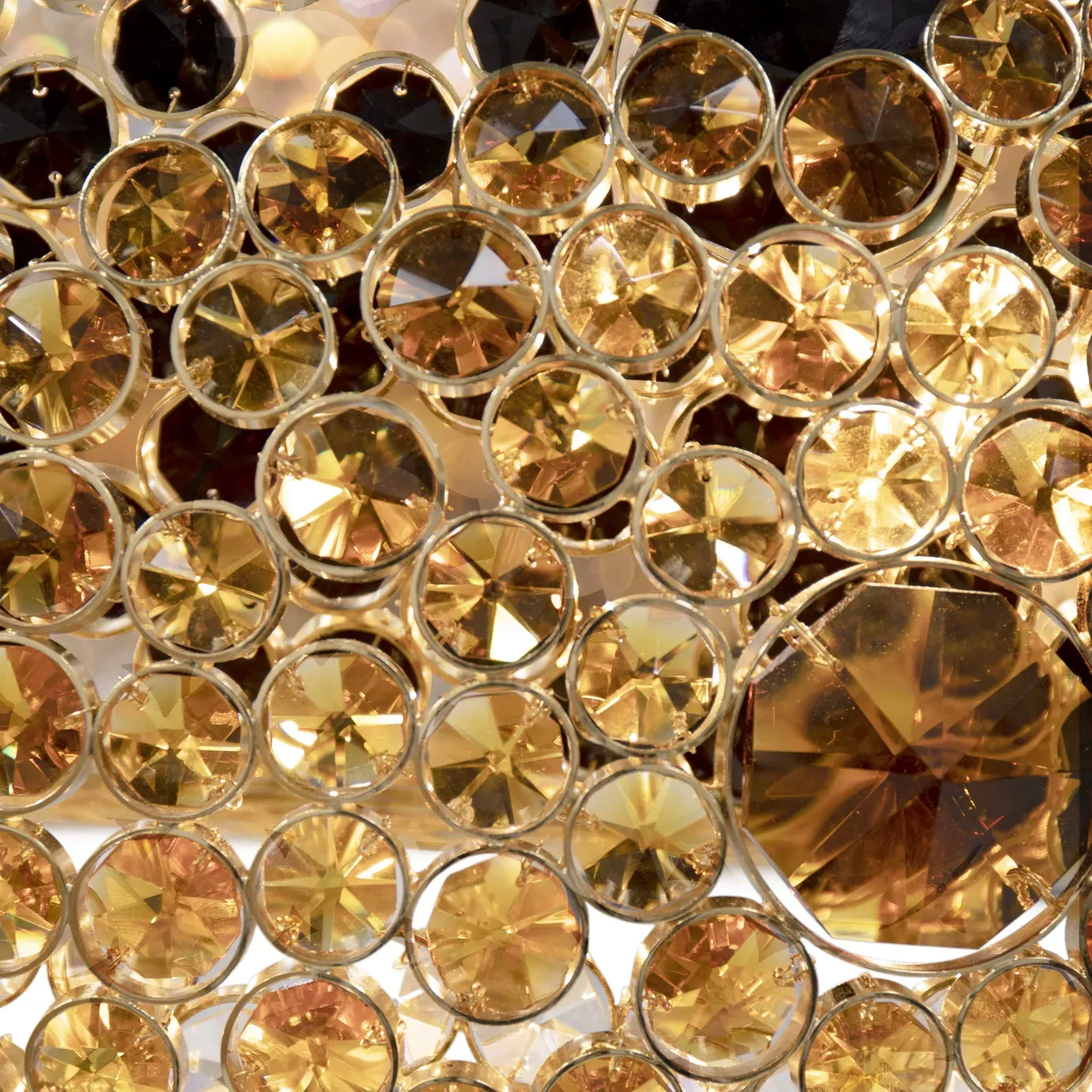 Elegant close-up detail of the faceted golden and black crystals that adorn the undulating rings of the Trinity Chandelier, showcasing their brilliance and precise cut