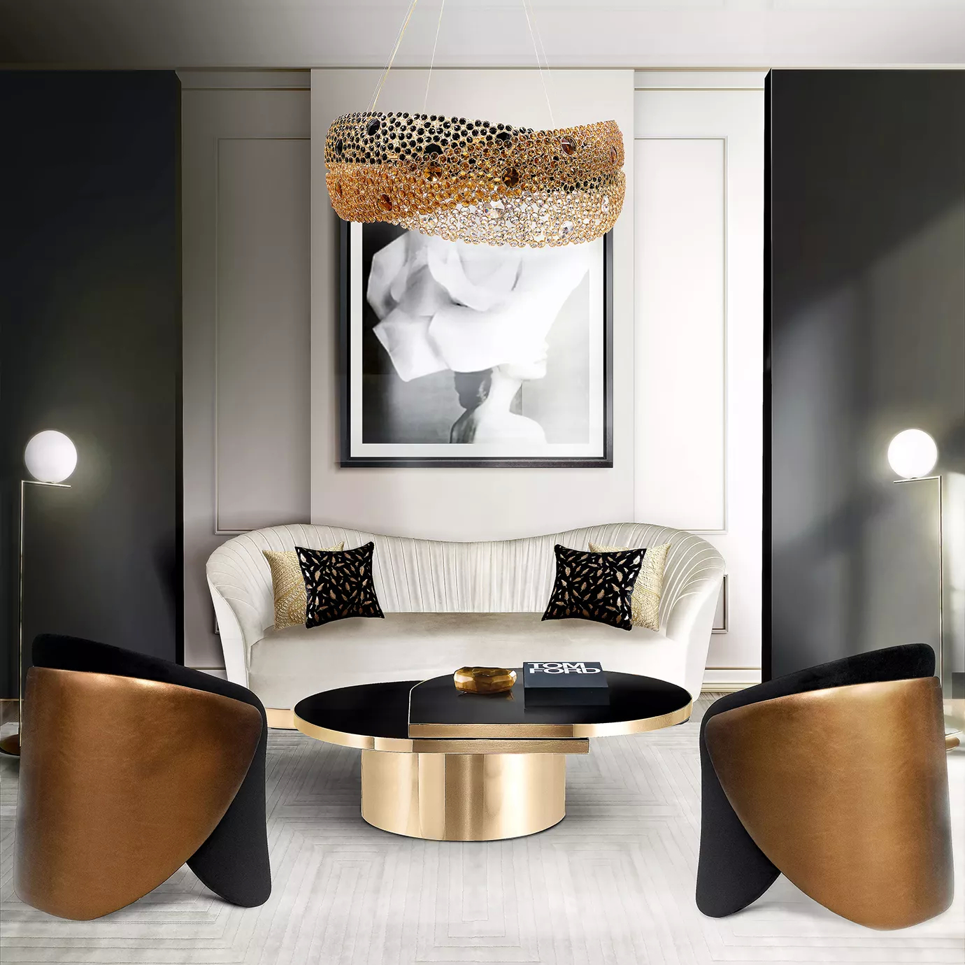 Elegant and modern living room featuring the Trinity Chandelier suspended above a black oval coffee table with a golden base, surrounded by a white curved sofa with black and golden pillows and two black and golden upholstered armchairs, in a space with grey-toned walls, a large framed picture with a black and white image, and two floor lamps with white globes.