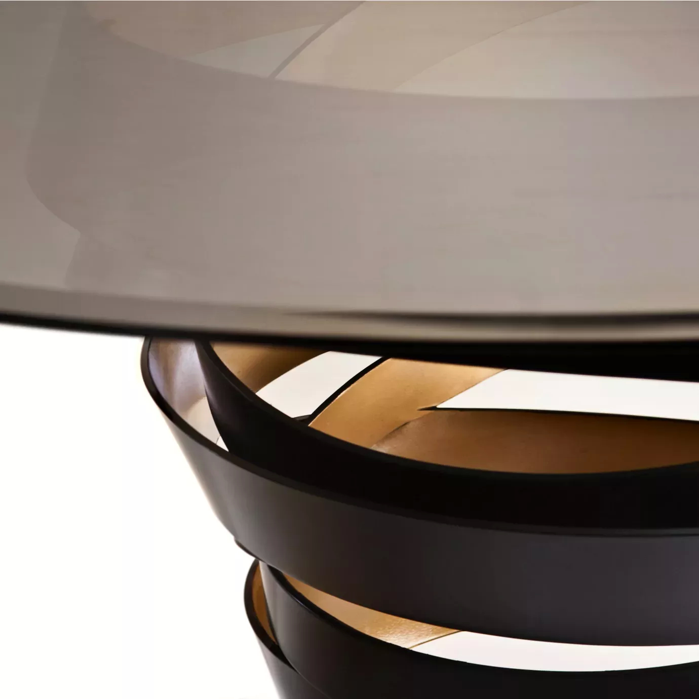 Detailed look on the Intuition Dining Table, showcasing its smoked glass tabletop and the two-toned metal structure, in black and golden tones.