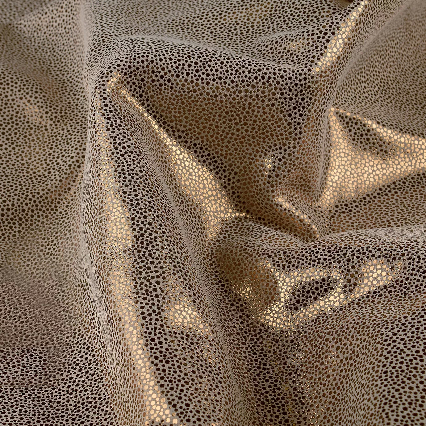 Elegant close-up of a Crico Leather swatch with a textured pattern of small dots in beige and metallic gold tones, featuring a smooth surface with a subtle shimmer, evoking a feeling of understated luxury and textured elegance.