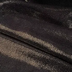 Close-up Pixel Gold Leather: textured black leather with small, shiny golden dots. Features soft folds and light reflections.