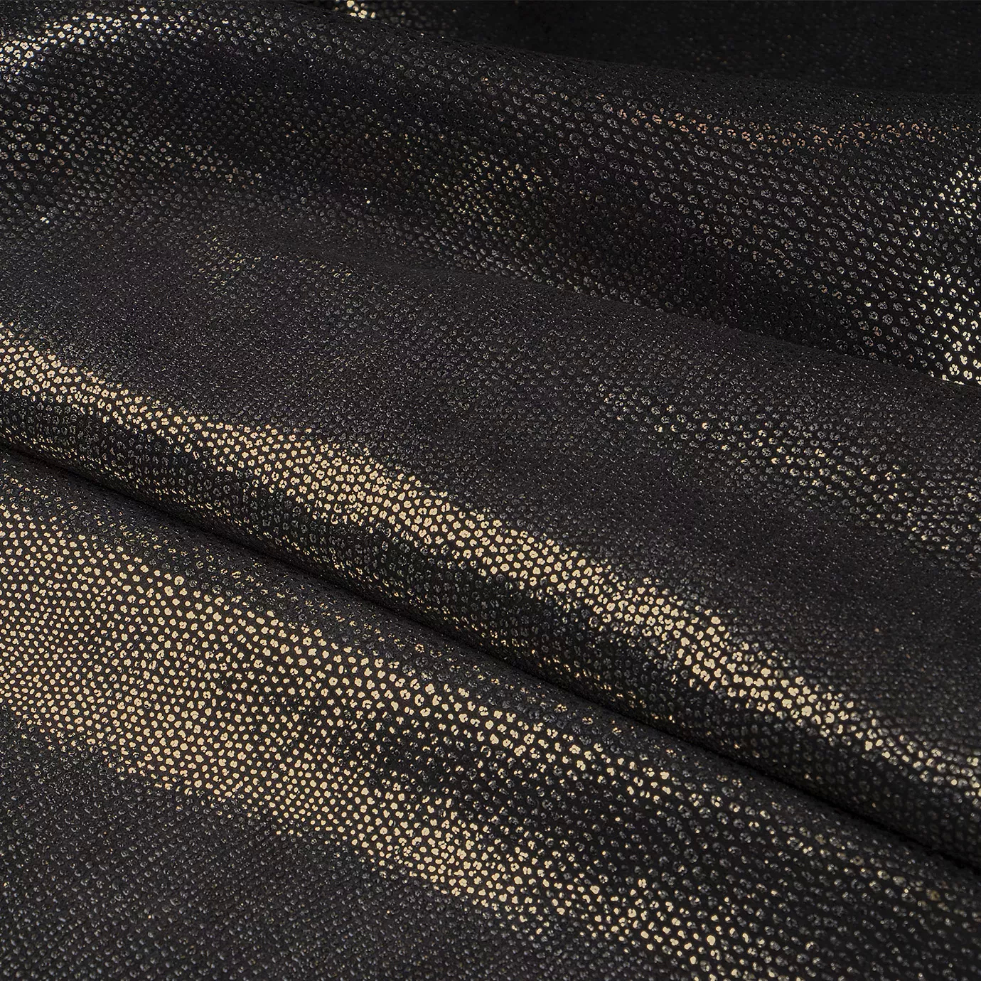 Close-up Pixel Gold Leather: textured black leather with small, shiny golden dots. Features soft folds and light reflections.
