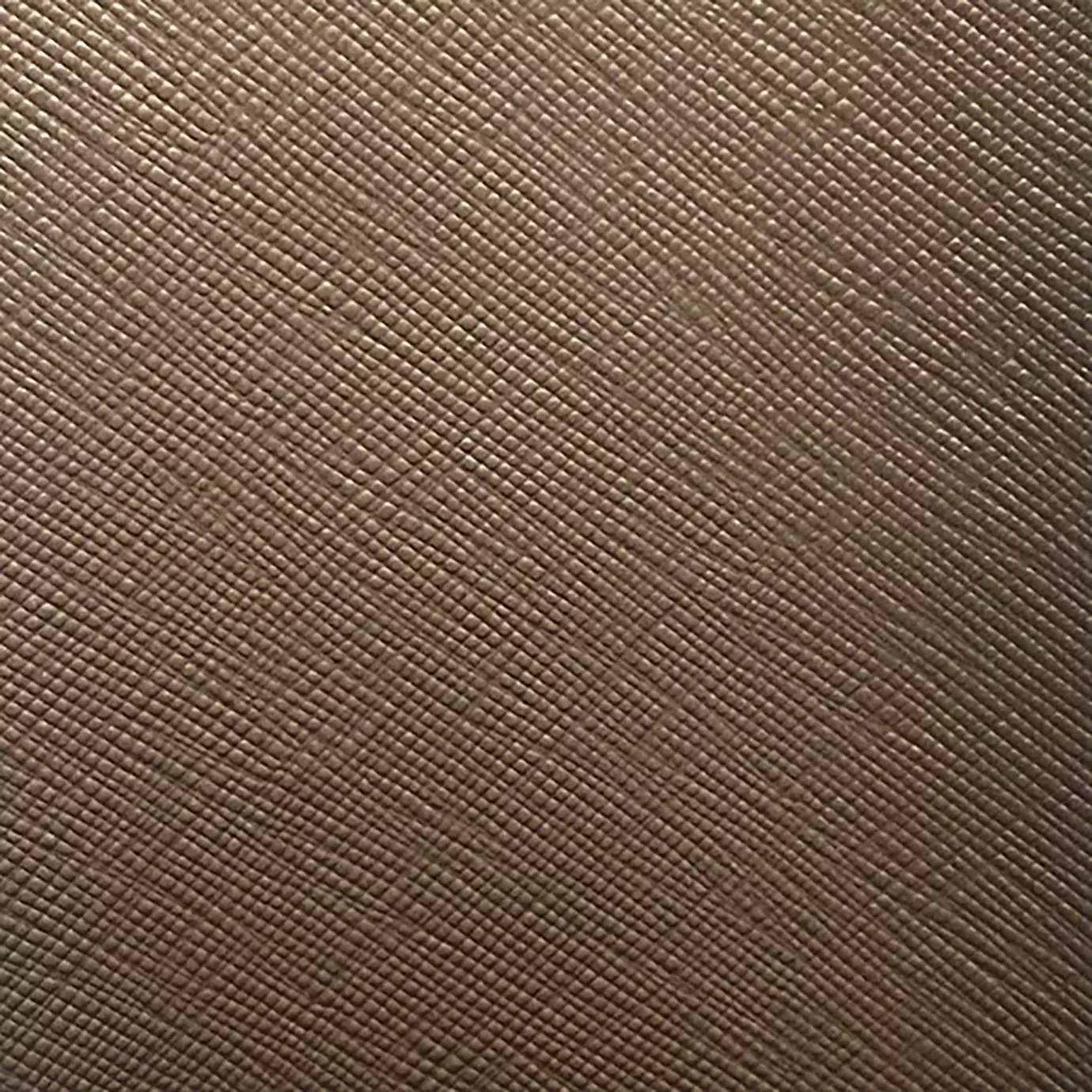 A close-up of Nomad Synthetic Leather shows a finely textured surface with a subtle, diagonal cross-hatch pattern in a warm, neutral tone.