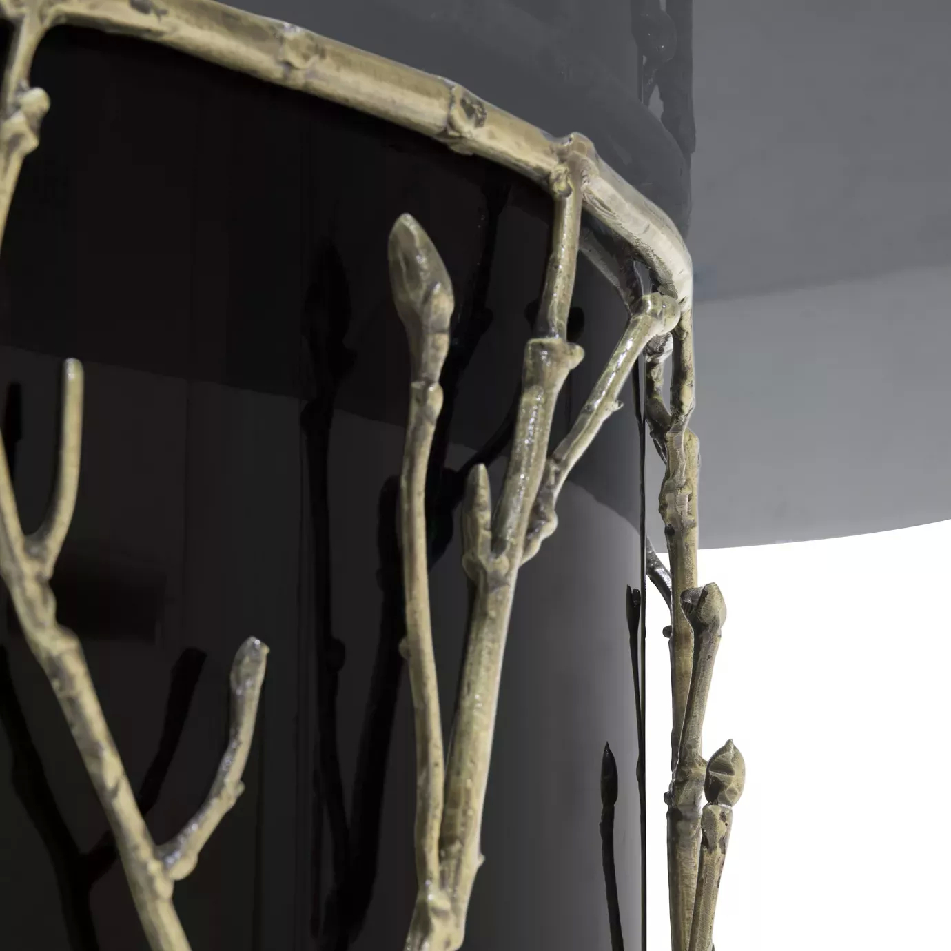 Enchanted Glass Top Dining Table: close look on the black structure adorned with intricate aged brass details, resembling branches.