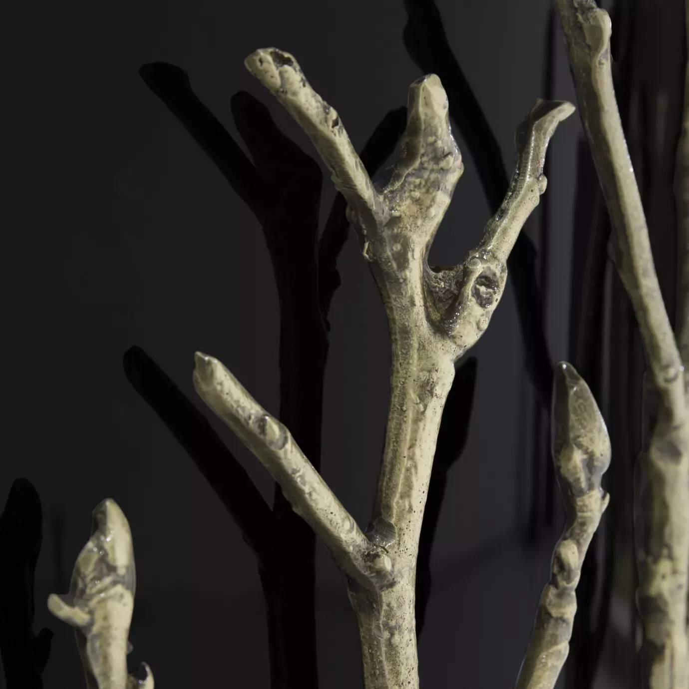 Detailed look on the intricate aged brass details, resembling branches, of the Enchanted Glass Top Dining Table, contrasting with the black structure.