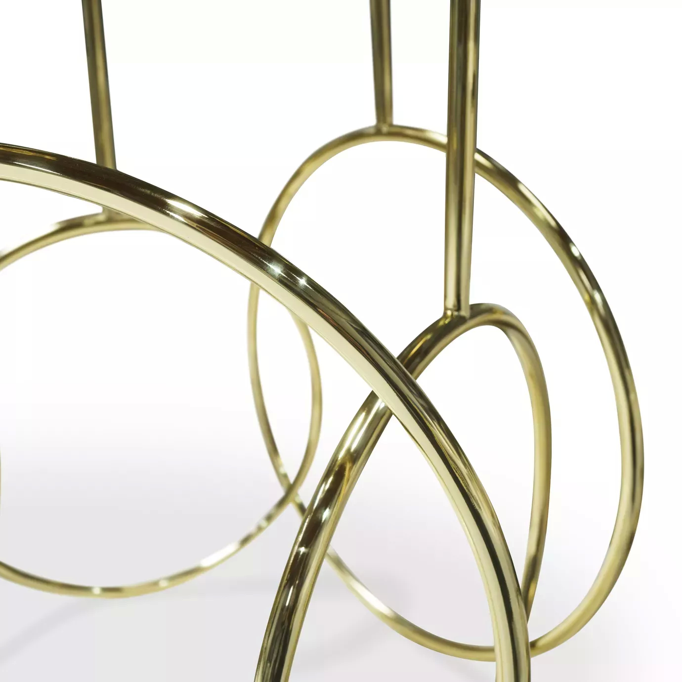 Elegant close-up of the sculptural golden base of the Kiki Side Table with interlocking circular details.