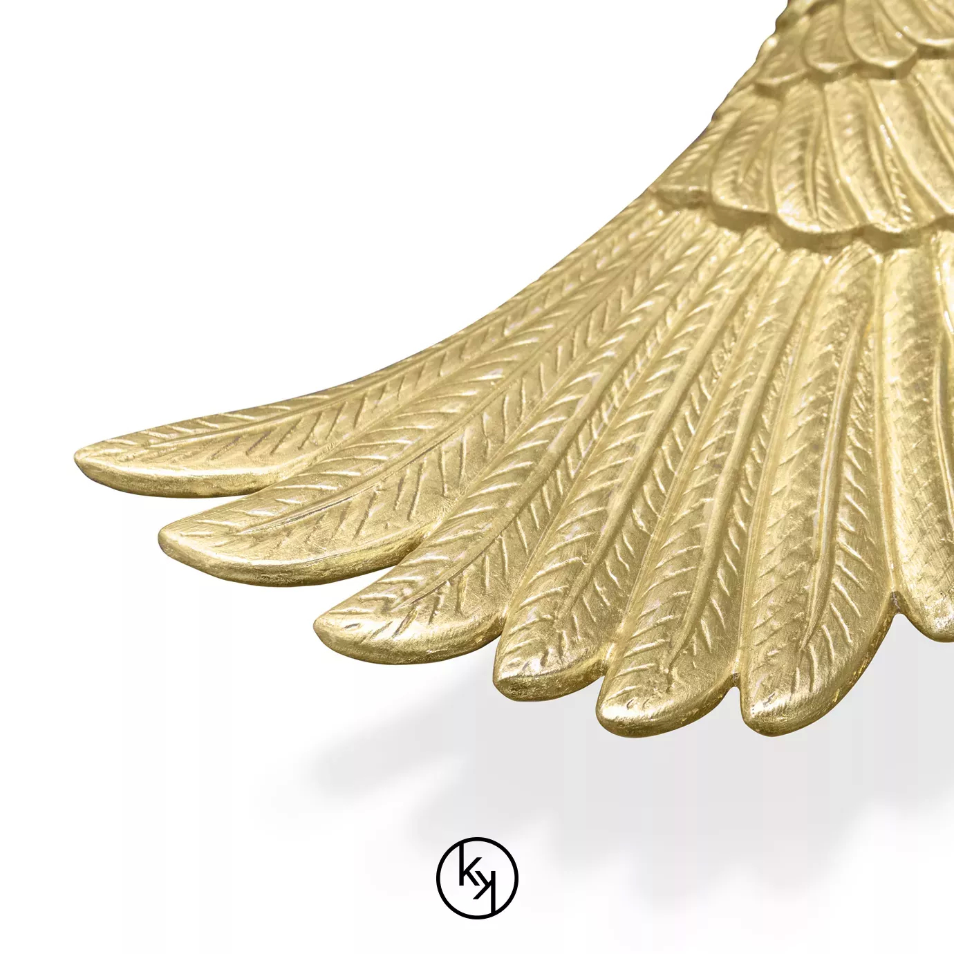Close up of Pluma Sconce by KOKET featuring sculptural golden wings with detailed featherwork, symmetrically arranged in a radiant, angelic design