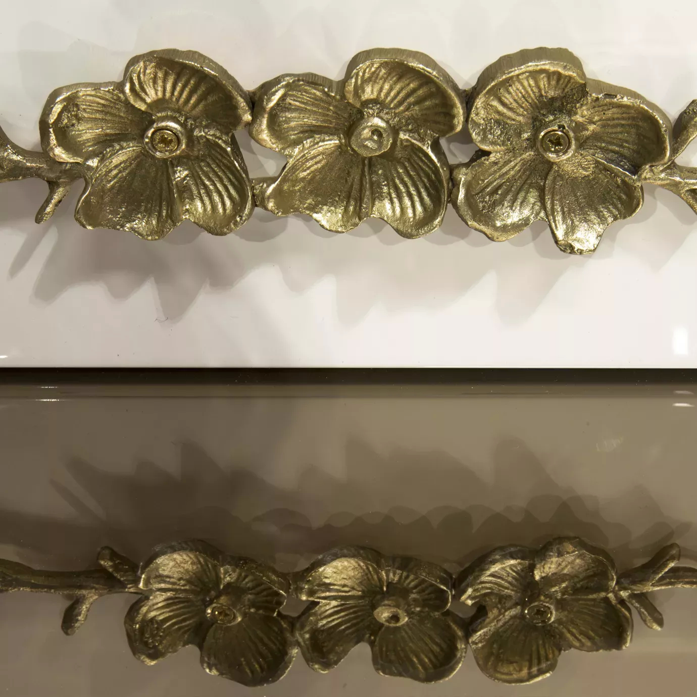 Close look on the golden floral themed adorns present on the drawers of the Spellbound Lacquer Bar Cabinet.