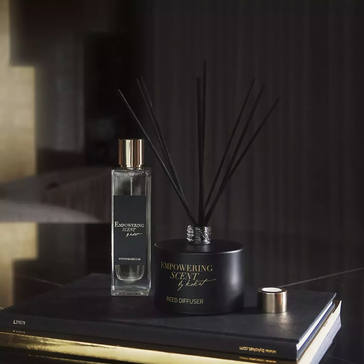 Empowering Scent set: black reed diffuser and matching perfume bottle with gold accents, displayed on a book.
