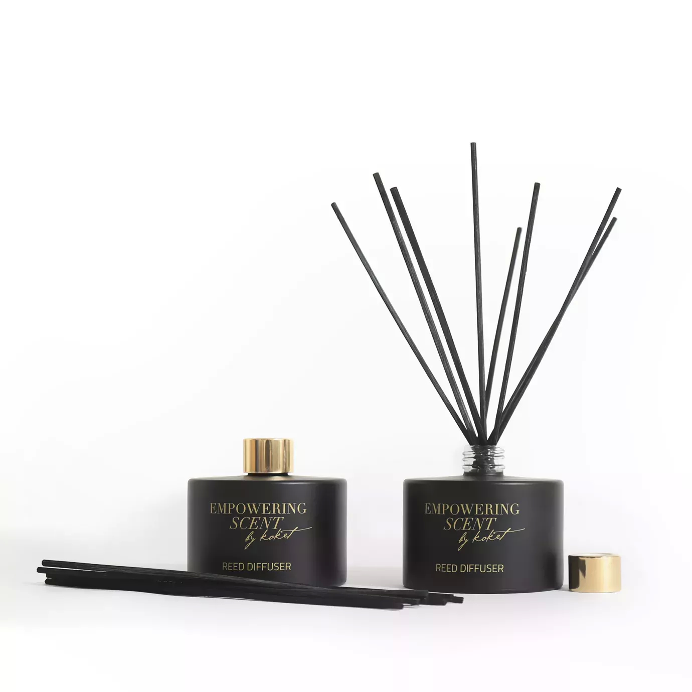 Two Empowering Diffusers: black bottles with gold accents and reeds, one with reeds inserted, the other with reeds beside it.