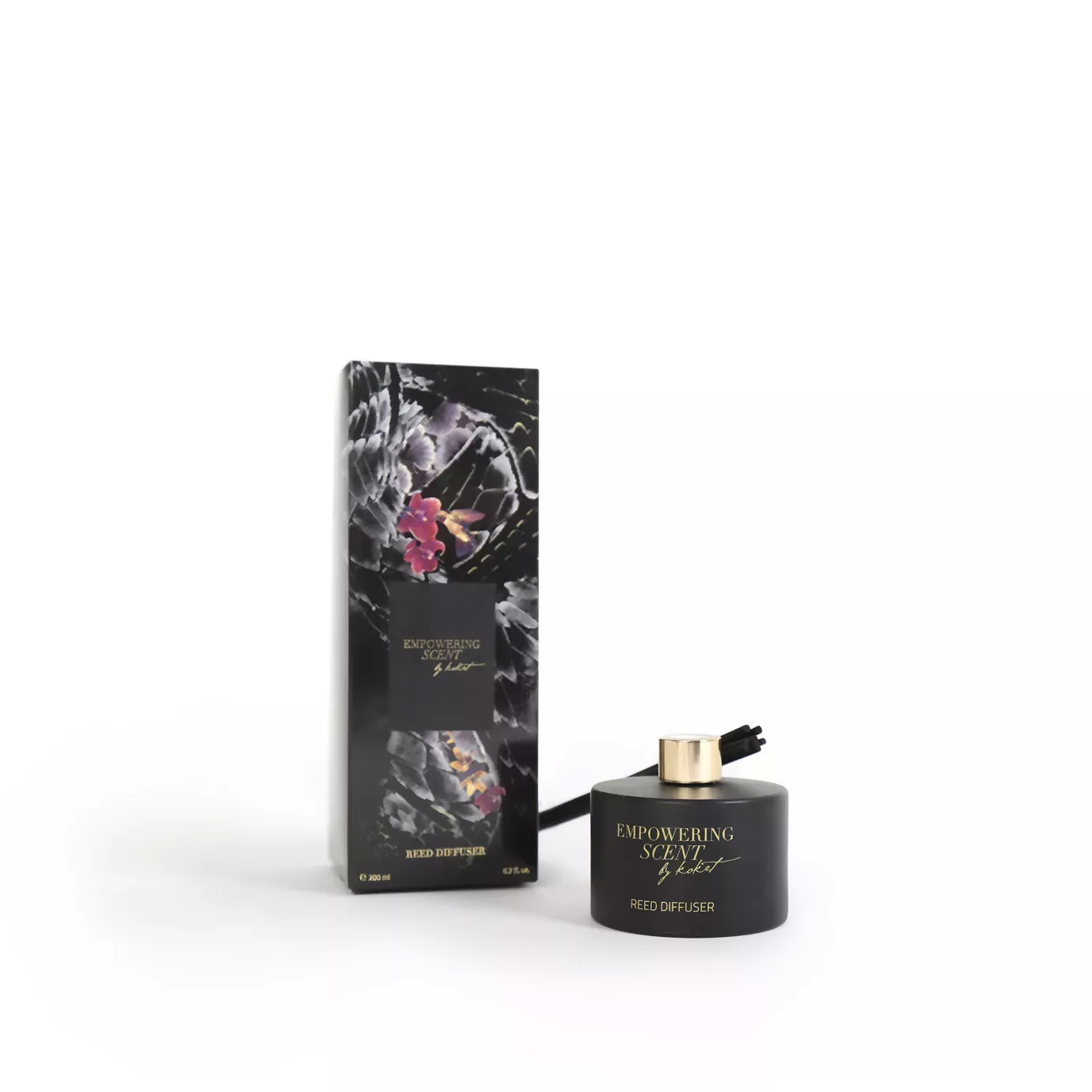 Empowering Diffuser with a black bottle, gold cap, and reeds, next to its packaging with floral and text details.