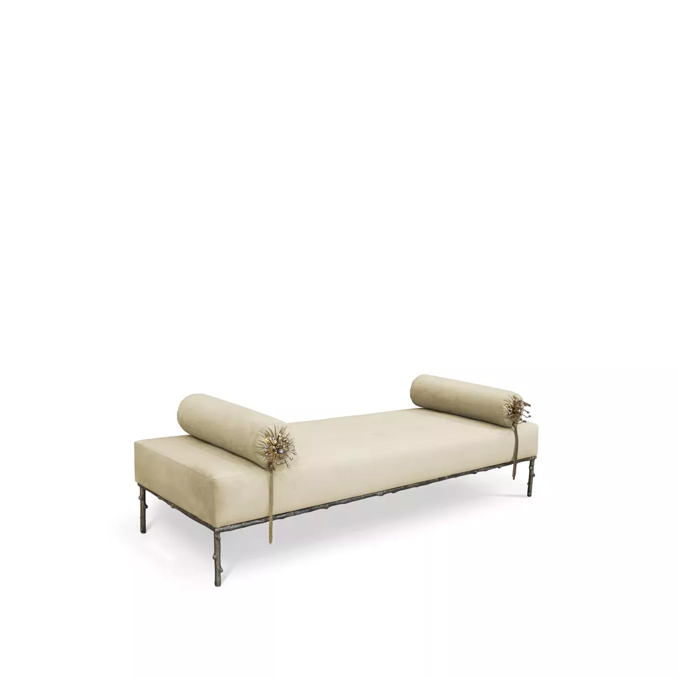 Slightly angled view of the Privê Bench, a cream velvet chaise with decorative bolster pillows and an ornate metal base.