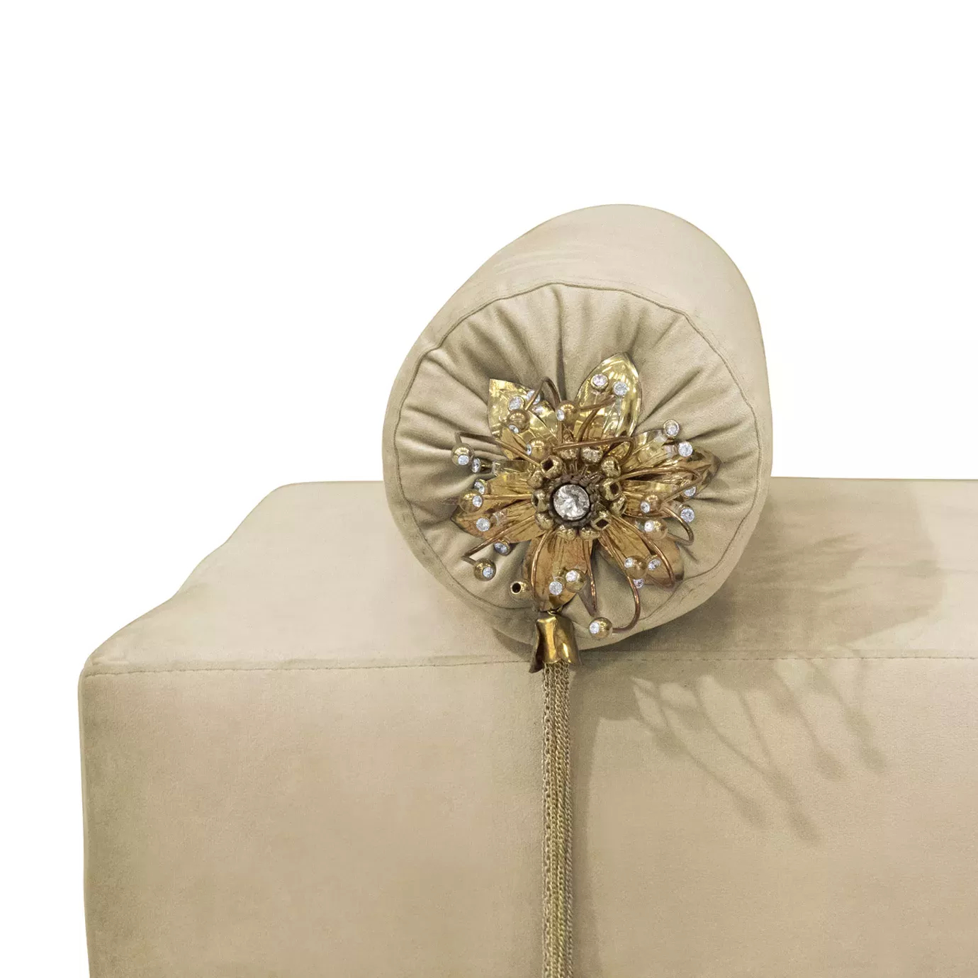 Close-up on the Privê Bench's cream velvet and a decorative bolster pillow with a jeweled golden flower and hanging tassels.