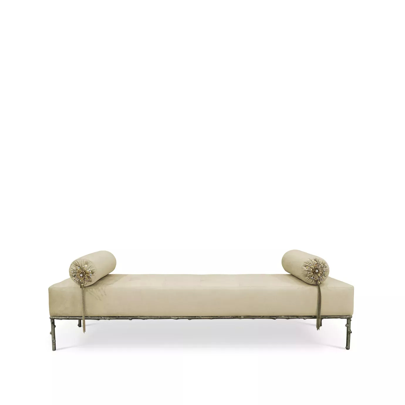 Privê Bench, a cream-colored velvet chaise lounge with two decorative bolster pillows and a detailed metal base.