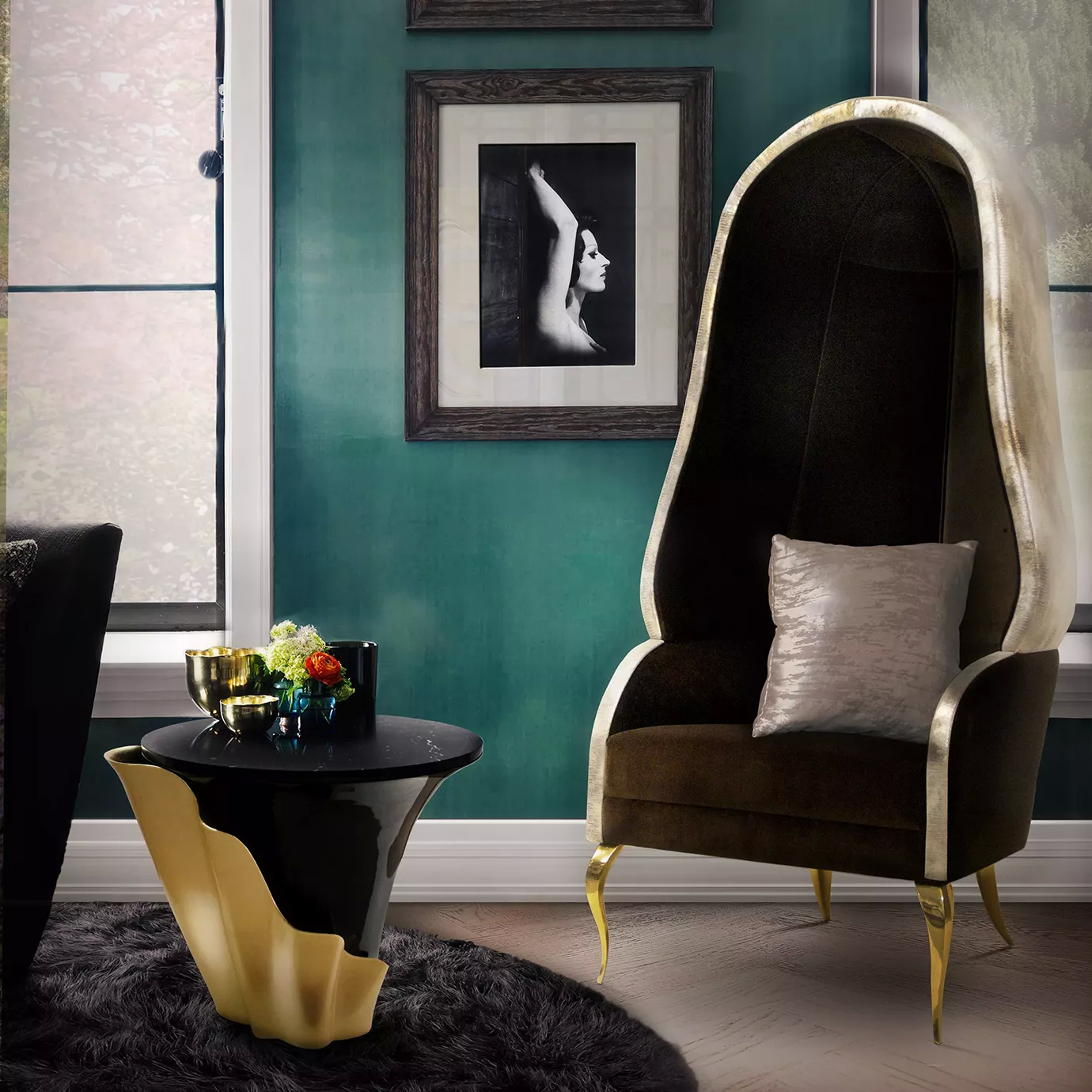 A modern living room with a luxurious side table, with a Yasmine Side Table. The side table has a black marble top, a black base and a golden structure attached around it. On the table, there are decorative items. Next to the side table, there is a high-backed chair in neutral tones. The background showcases a teal wall adorned with black and white frames.