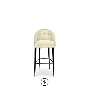 Aberdeen Bar Stool with a cream-colored, button-tufted seat and back, supported by sleek black legs with metallic accents.