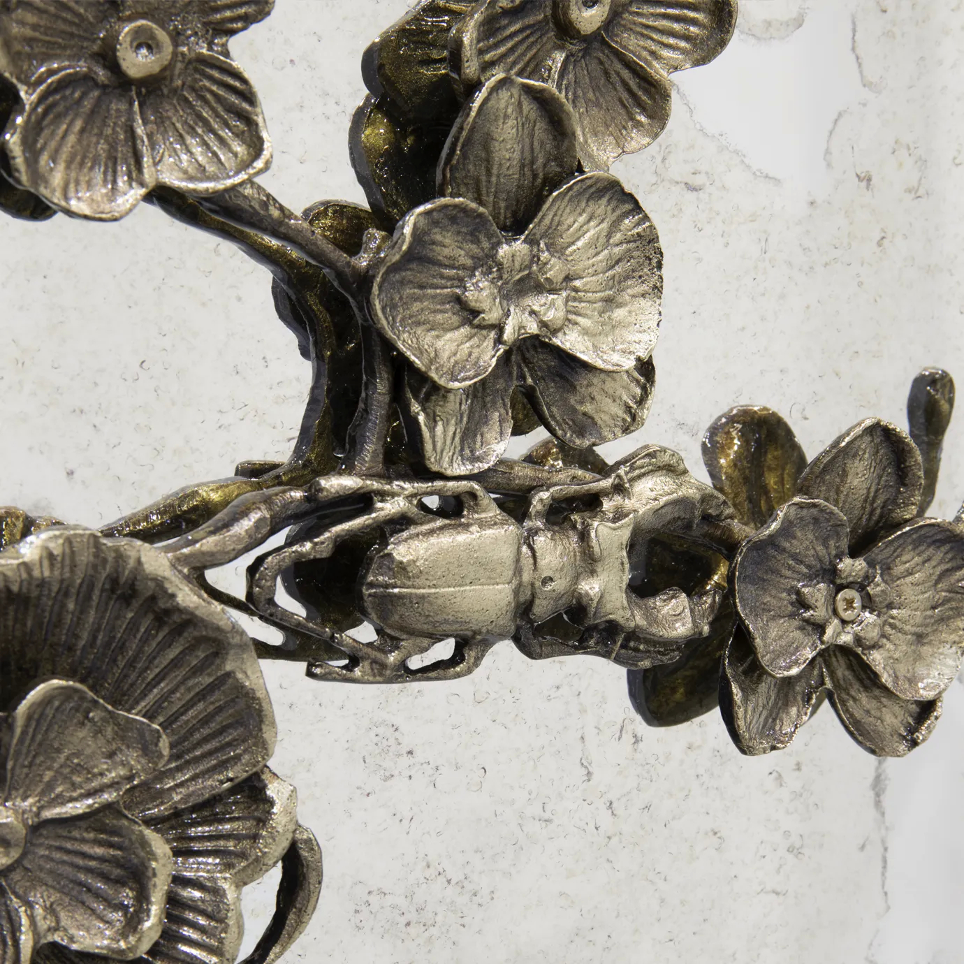 Close-up of the Spellbound Armoire, focusing on the intricate golden insect detail amidst the ornate floral design on the aged mirror.