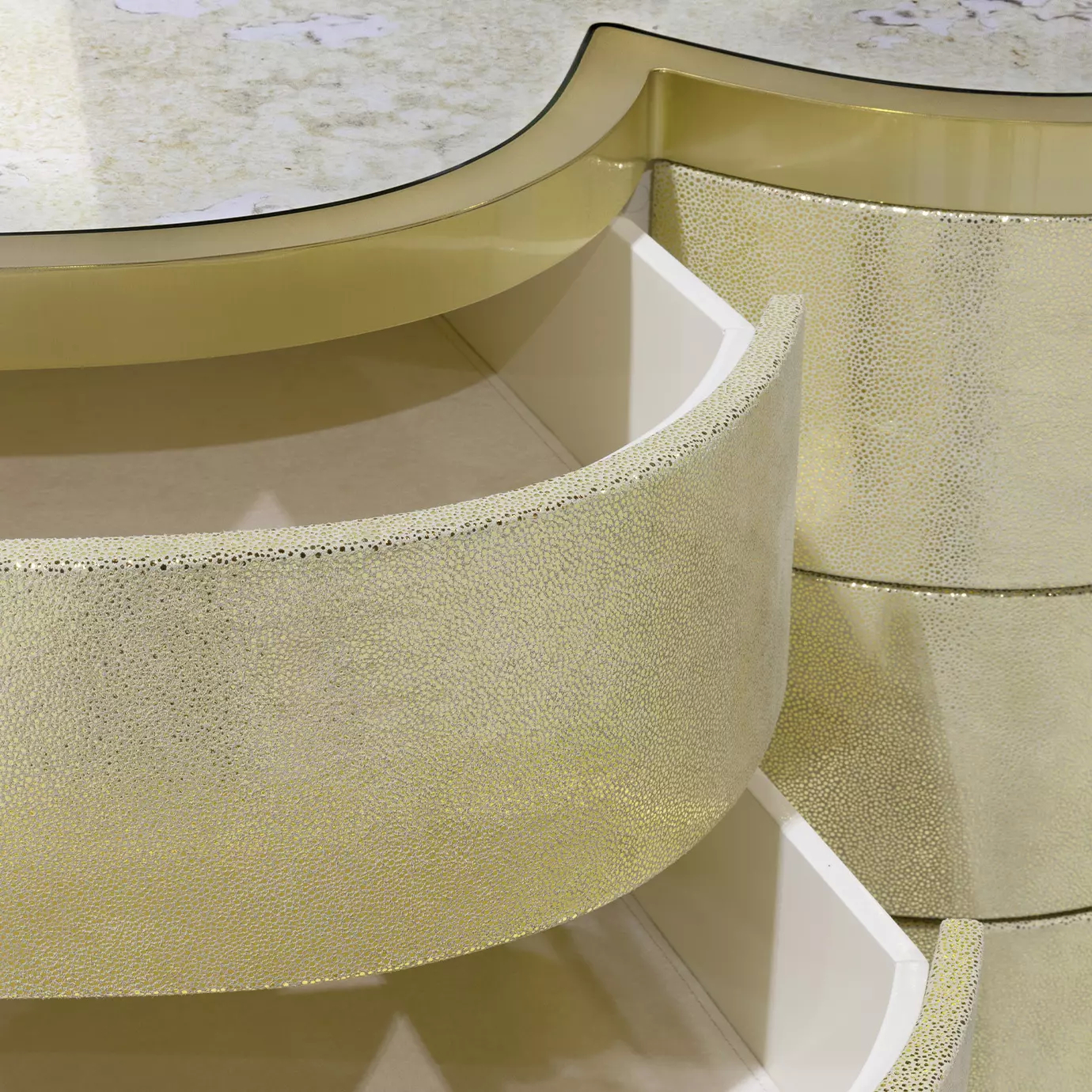 Close-up of the Poêm Chest, highlighting the textured golden drawer fronts, open white drawer interiors, and the patterned top surface.