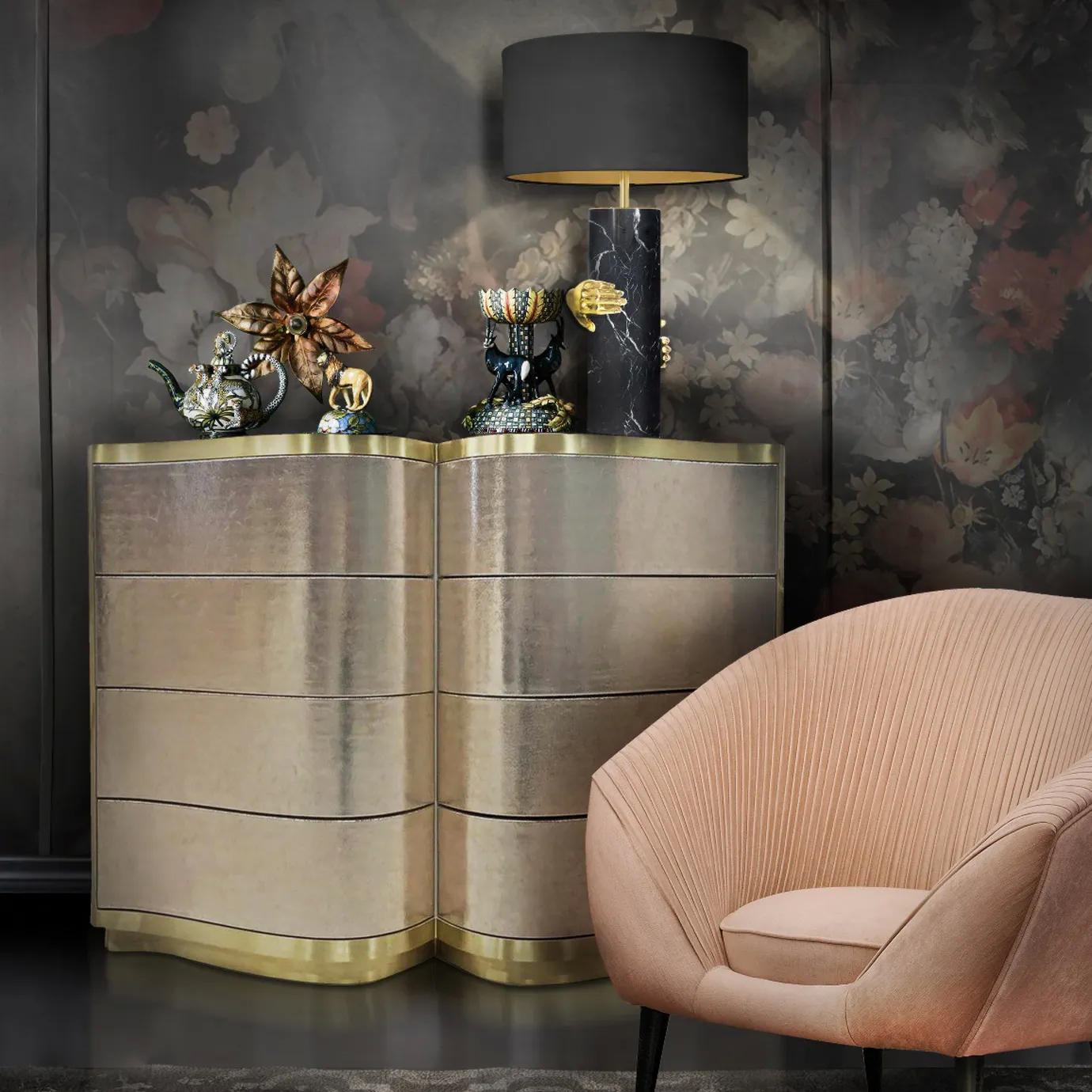 The Poêm Chest in a dimly lit, stylish room with a black and gold lamp, decorative objects, and a blush-toned armchair.