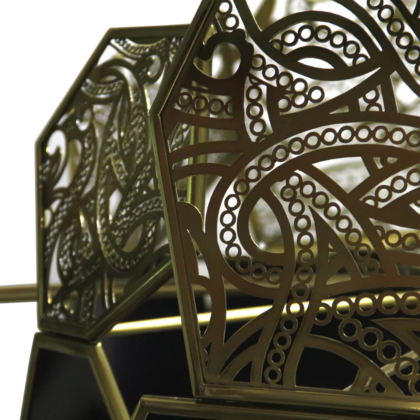 Extreme close-up of the Hypnotic Lacquer Chandelier's ornate golden metalwork with swirling, circular, and leafy cutouts.