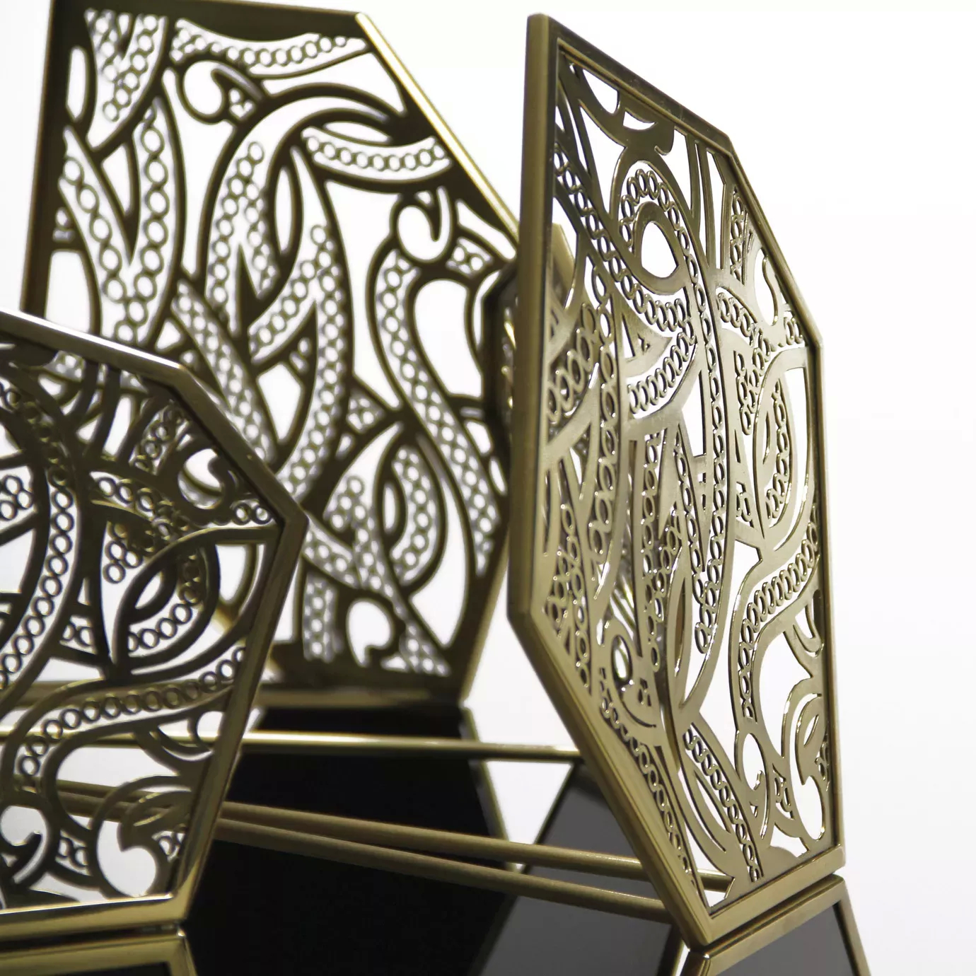 Intricate golden metalwork detail of the Hypnotic Lacquer Chandelier, with ornate cutouts and a hint of the black lacquer beneath.