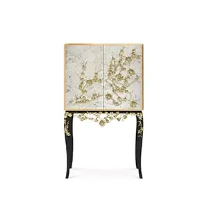 The Spellbound Aged Mirror Bar Cabinet features an elegant golden frame and golden flower-shaped details on its door elongating to its black base.