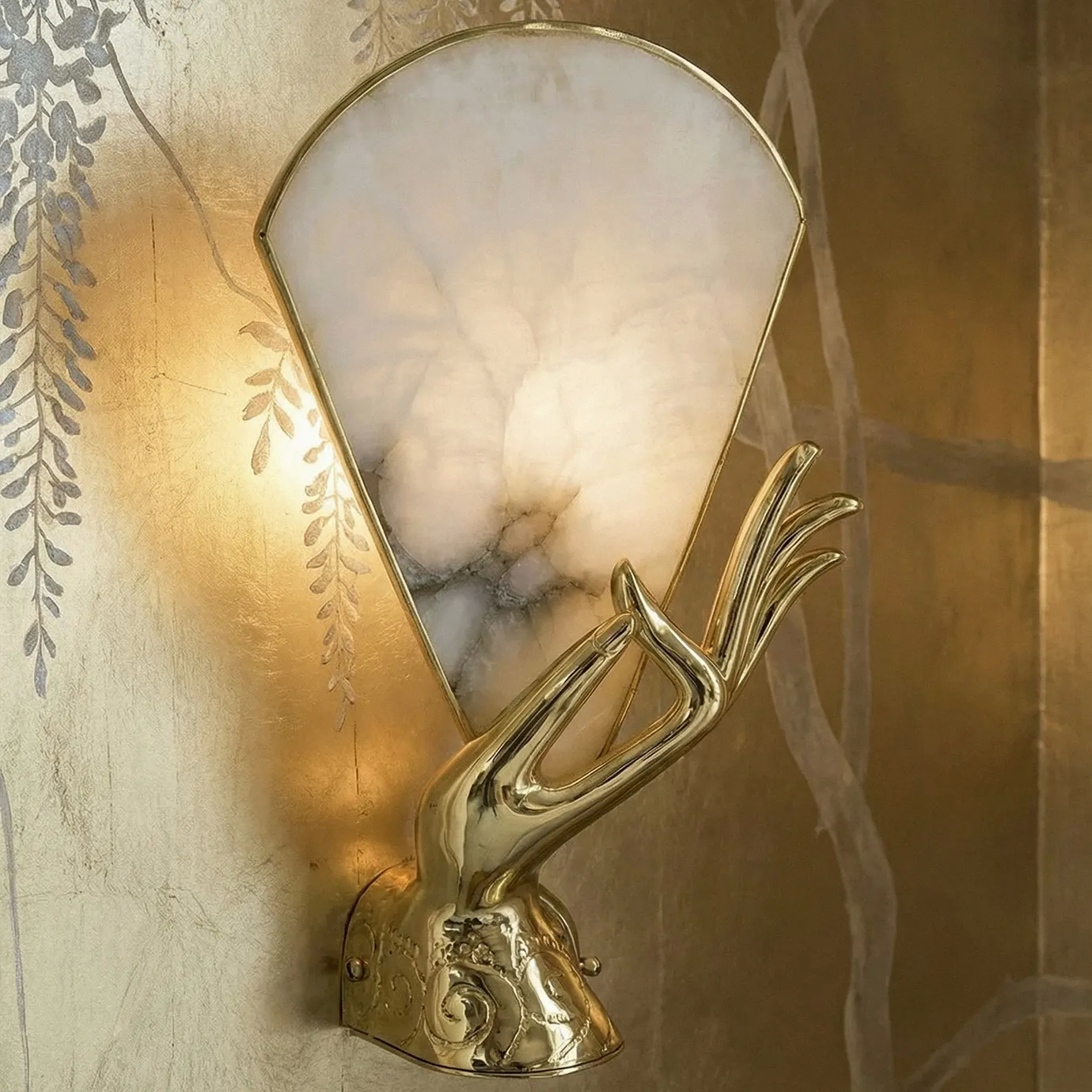 KOKET Neurotic wall sculpture in polished gold brass, featuring a fluid, abstract folded-ribbon design on a white architectural wall.