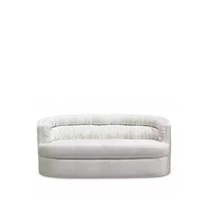 A small, white sofa with a curved back and a simple design, featuring a distinctive, ruched texture, known as the Cocktail Sofa.