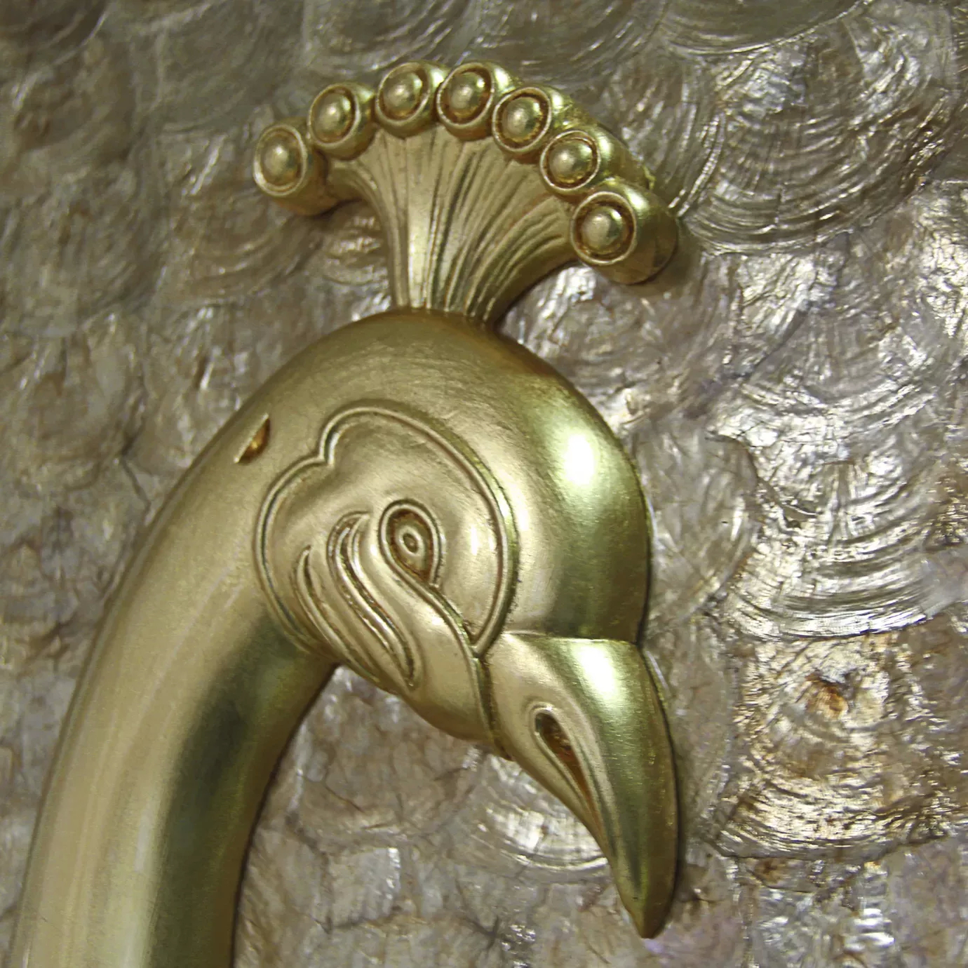 Elegant close-up of the golden peacock head on the Camilia armoire.