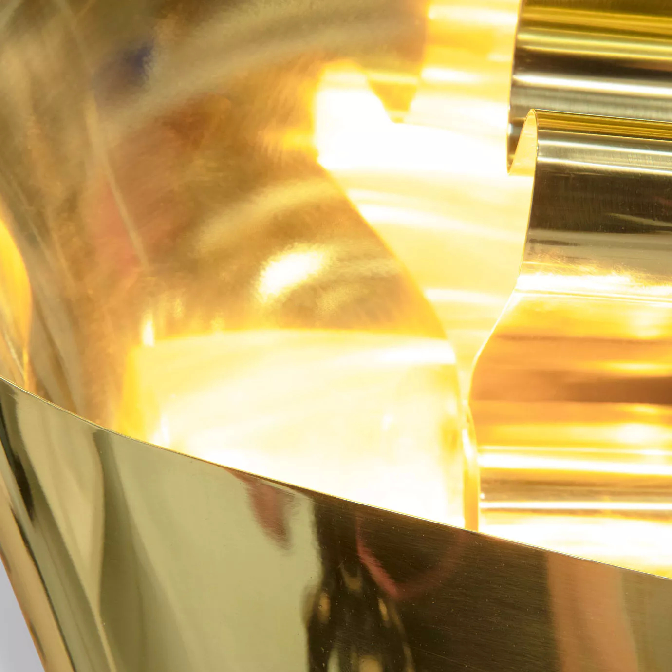 An abstract detail of the polished gold, showing its flowing curves and the luminous reflections within its form.