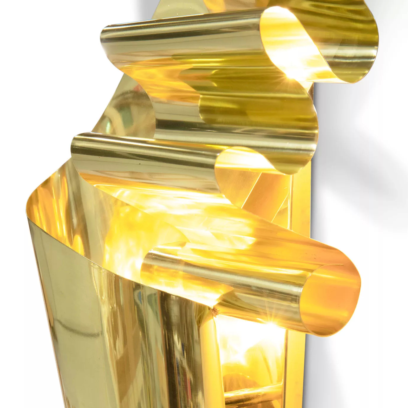 Close-up on the polished gold sculpture, highlighting its flowing curves and the bright reflections on its surface.