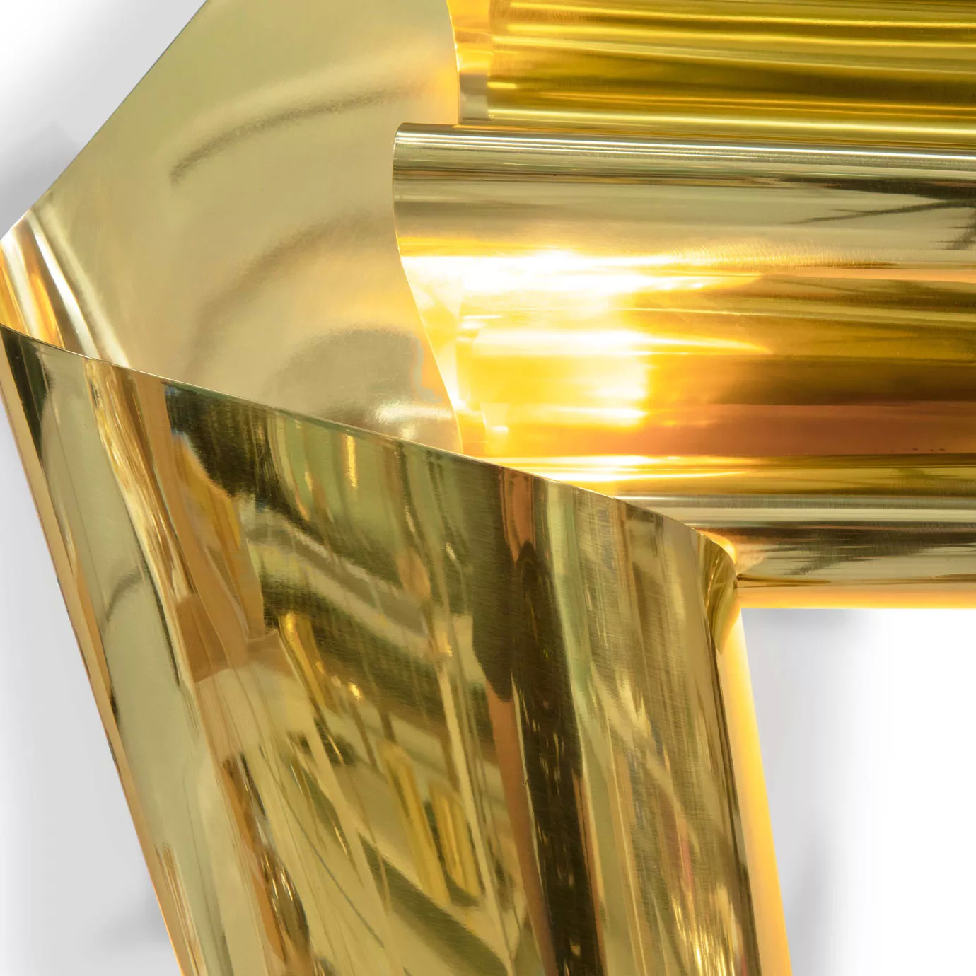 A very close view of the polished gold sculpture, showing the intense reflections and sharp angles of its abstract form.