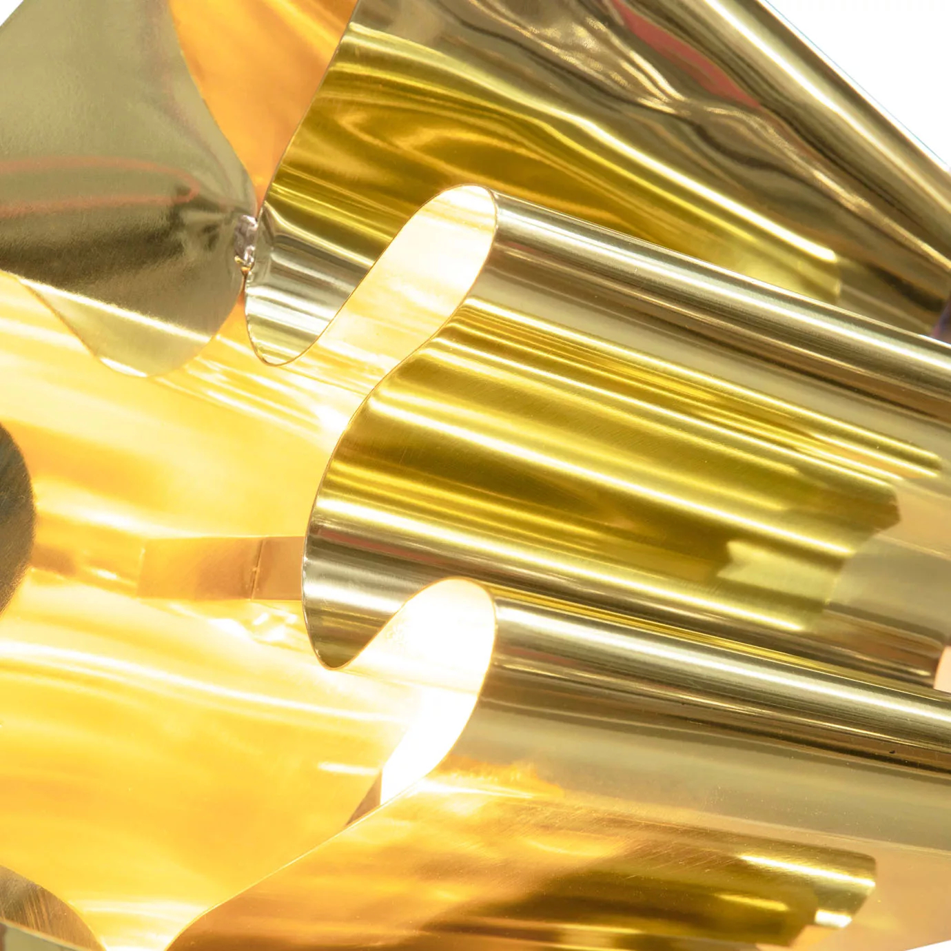 Extreme close-up revealing the interior curves and bright reflections within the polished gold abstract sculpture.
