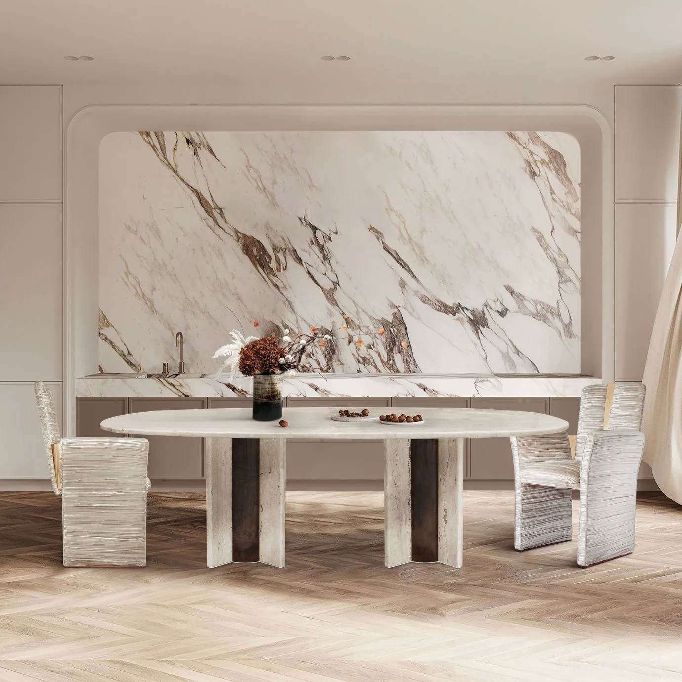Paris Travertine Marble Oval Dining Table by KOKET in a modern dining room with herringbone wood flooring, elegant travertine marble wall, and stylish upholstered chairs.