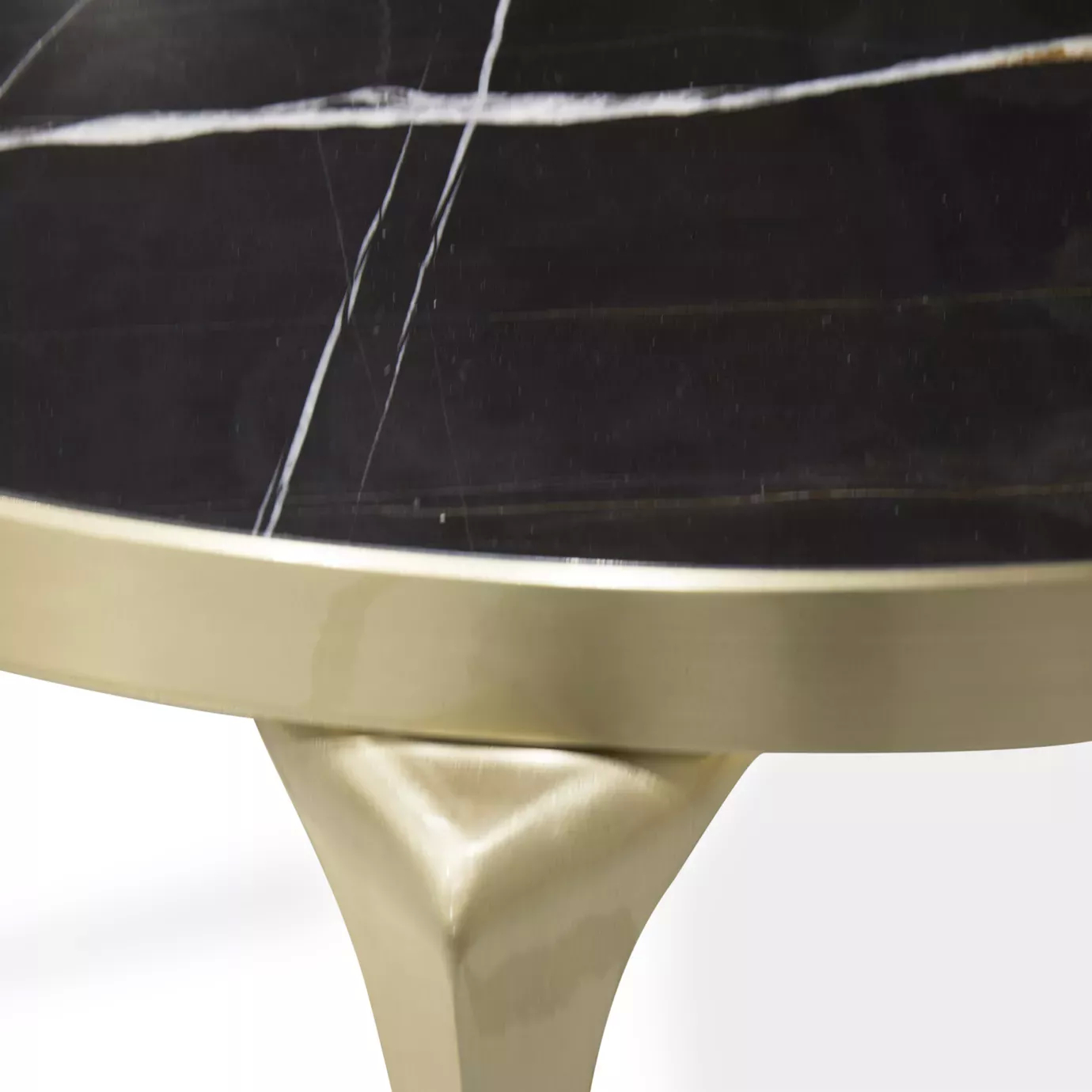 Elegant detail of the Sahara Noir marble top and golden base of the Rita table.