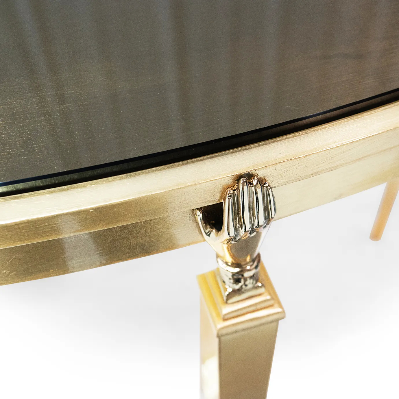 Gisele Console's delicate gold hand detail where the elegant leg meets the sleek, dark tabletop.