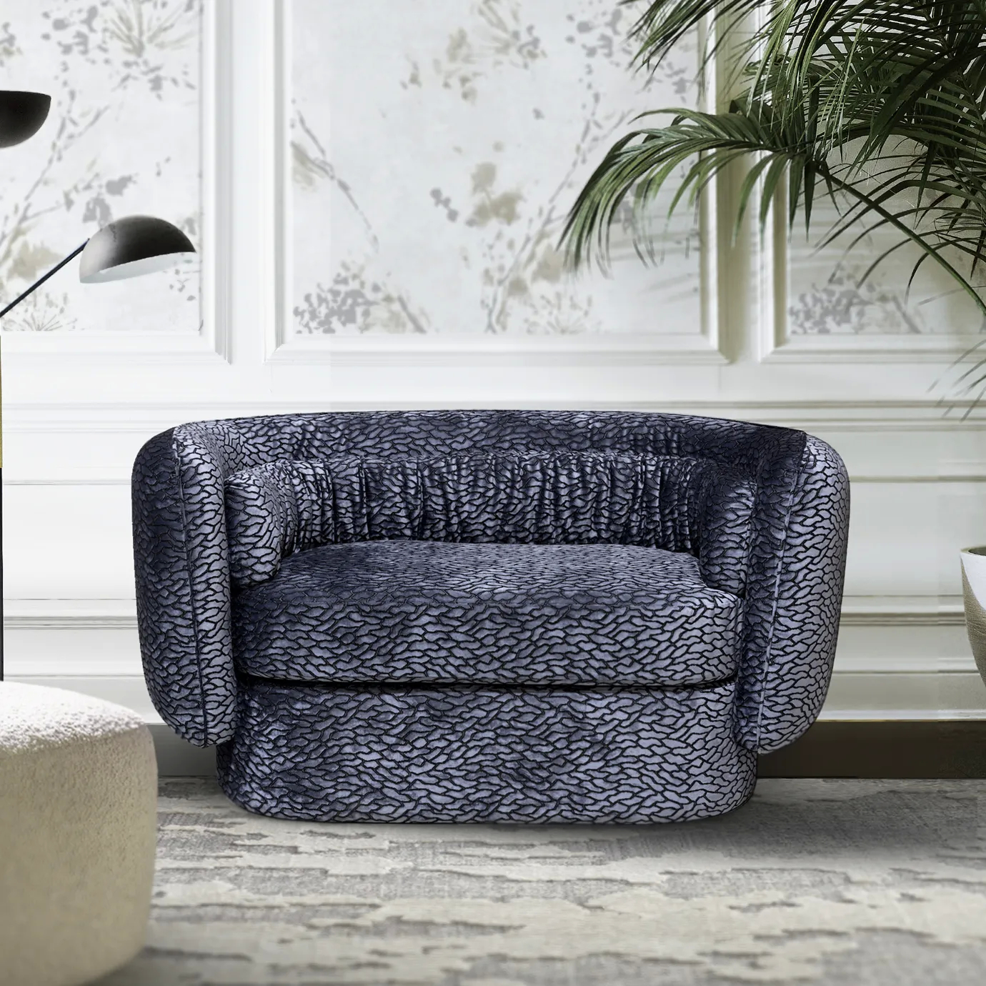 The Deb Loveseat, with its textured upholstery and draped detail, sits in an elegant room with patterned wallpaper and lush greenery.